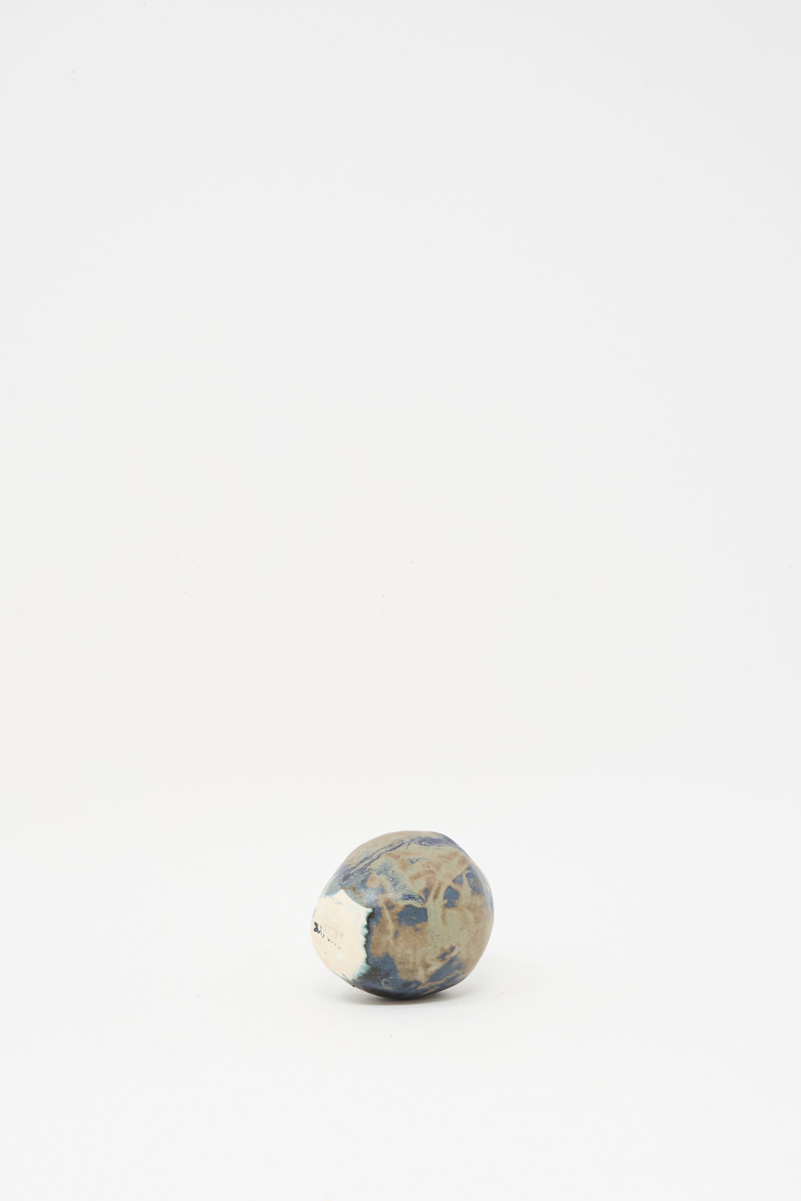 The MONDAYS Mini Bud Vase I, a round, earth-toned piece featuring blue and beige patterns like a hand-built porcelain vase with subtle blue glaze, is displayed at the center of a plain white background.