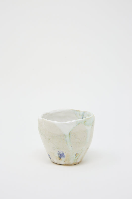 A small Porcelain Tumbler with Blue Dot by MONDAYS, textured glaze and blue and white flowers on it.