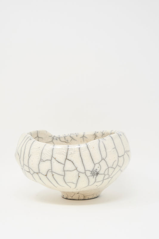 The MONDAYS Raku Coiled Bowl is a white ceramic piece with a rounded shape and a unique crackle glaze, shown against a plain white background.