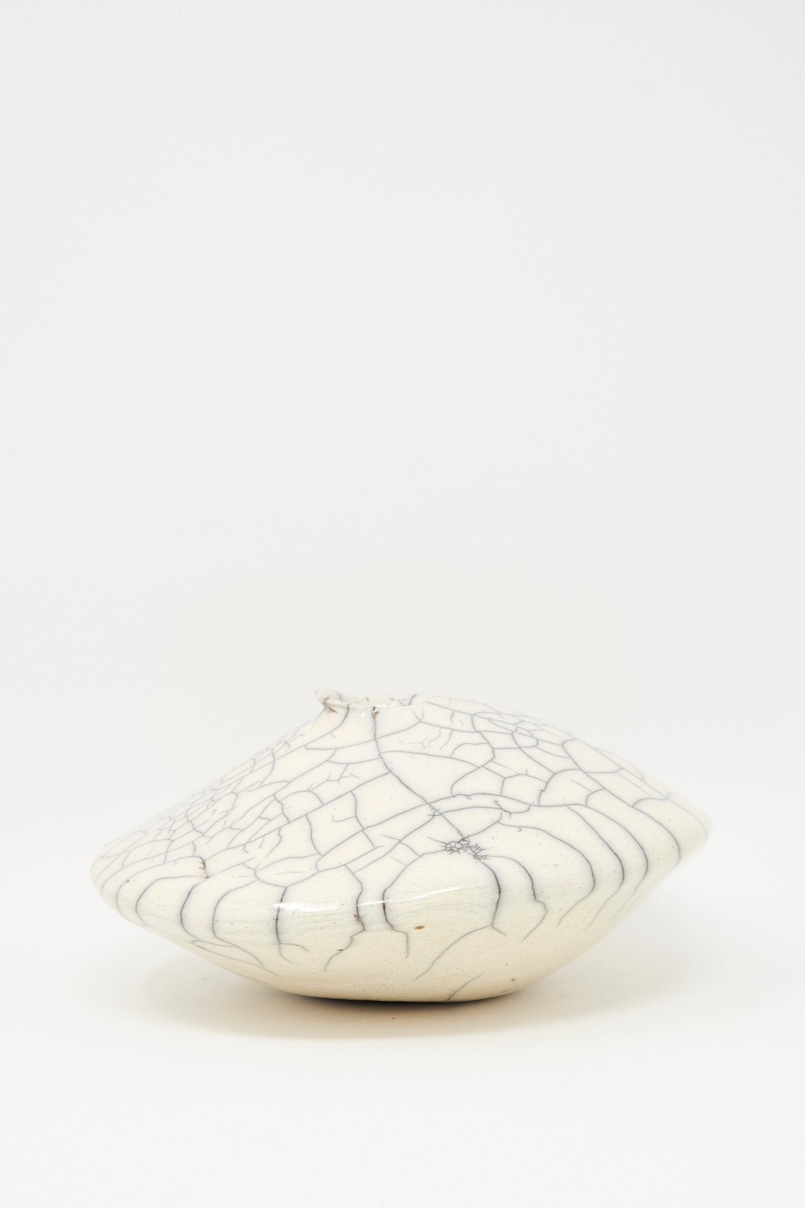 The MONDAYS Raku Ikebana Vase Large is a white, round, flat stoneware vase with a small opening and crackled glaze, crafted using Raku firing. Not water-safe and shown on a plain white background.
