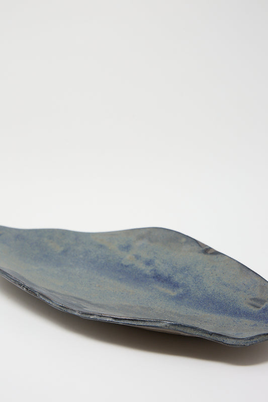 A Shell Platter in Blue Glaze on Dark Brown Clay by MONDAYS on a white surface.