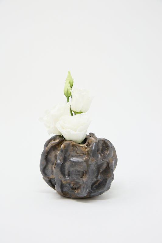 A MONDAYS handmade Urchin Vessel in Glazed Stoneware with white flowers on a white background.