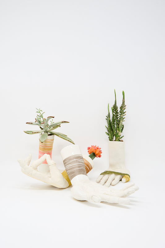The Monty J Ceramic Hand Sculpture with Grey Thread is handmade in Brooklyn, shaped like human hands and arms to cradle succulents or cacti, featuring subtle grey thread against a plain white finish.