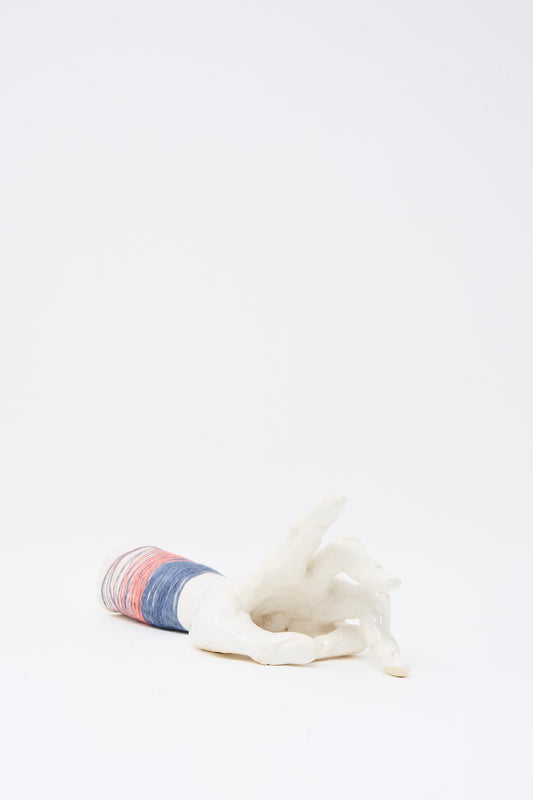 The Ceramic Hand Sculpture with Pink and Blue Thread by Monty J lies on its side against a plain white background, handmade in Brooklyn.