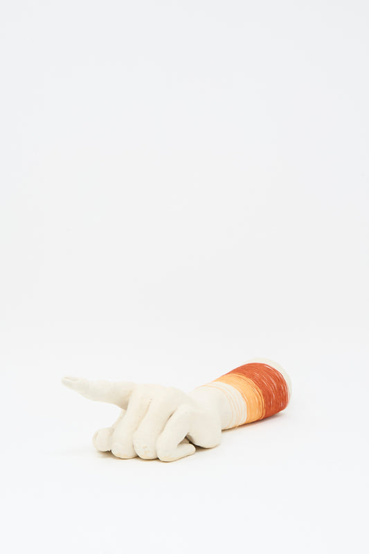 The Monty J Ceramic Hand Sculpture with Orange and Red Thread rests on its side, index finger extended, featuring gradient orange and red accents near the wrist, all set against a plain white background.