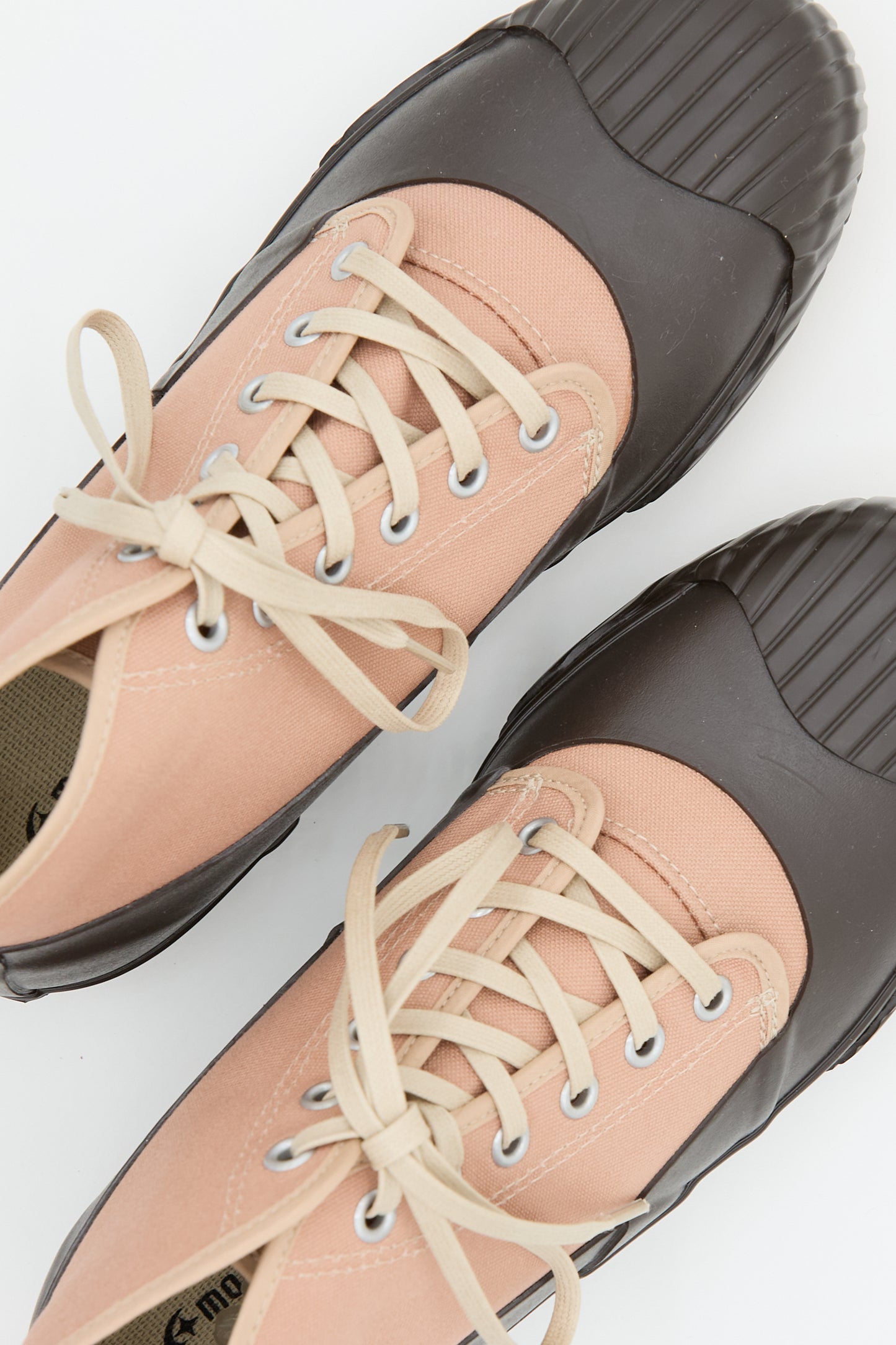 Close-up view of a pair of Moonstar Alweather Sneaker in Coral with pink canvas uppers and black rubber toe caps, handmade in Japan, on a white background.