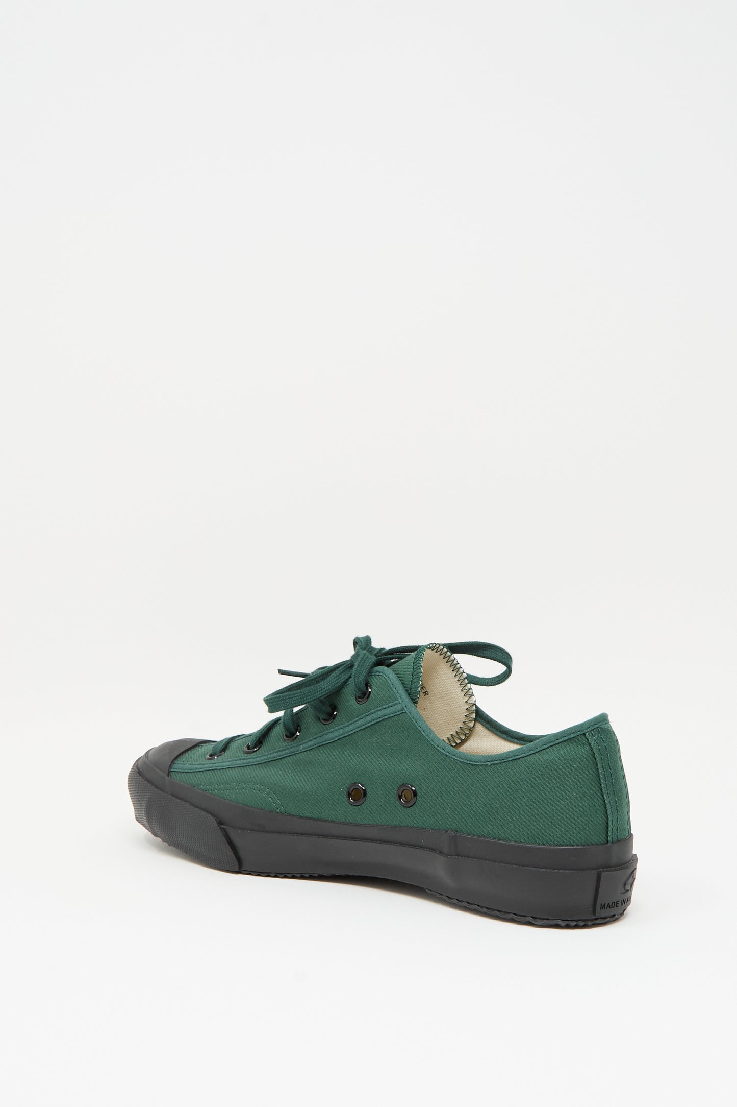 The Moonstar Gym Classic Sneaker in Dark Green features a green canvas low-top design, black rubber sole, and black eyelets, shown from the side against a plain white background.