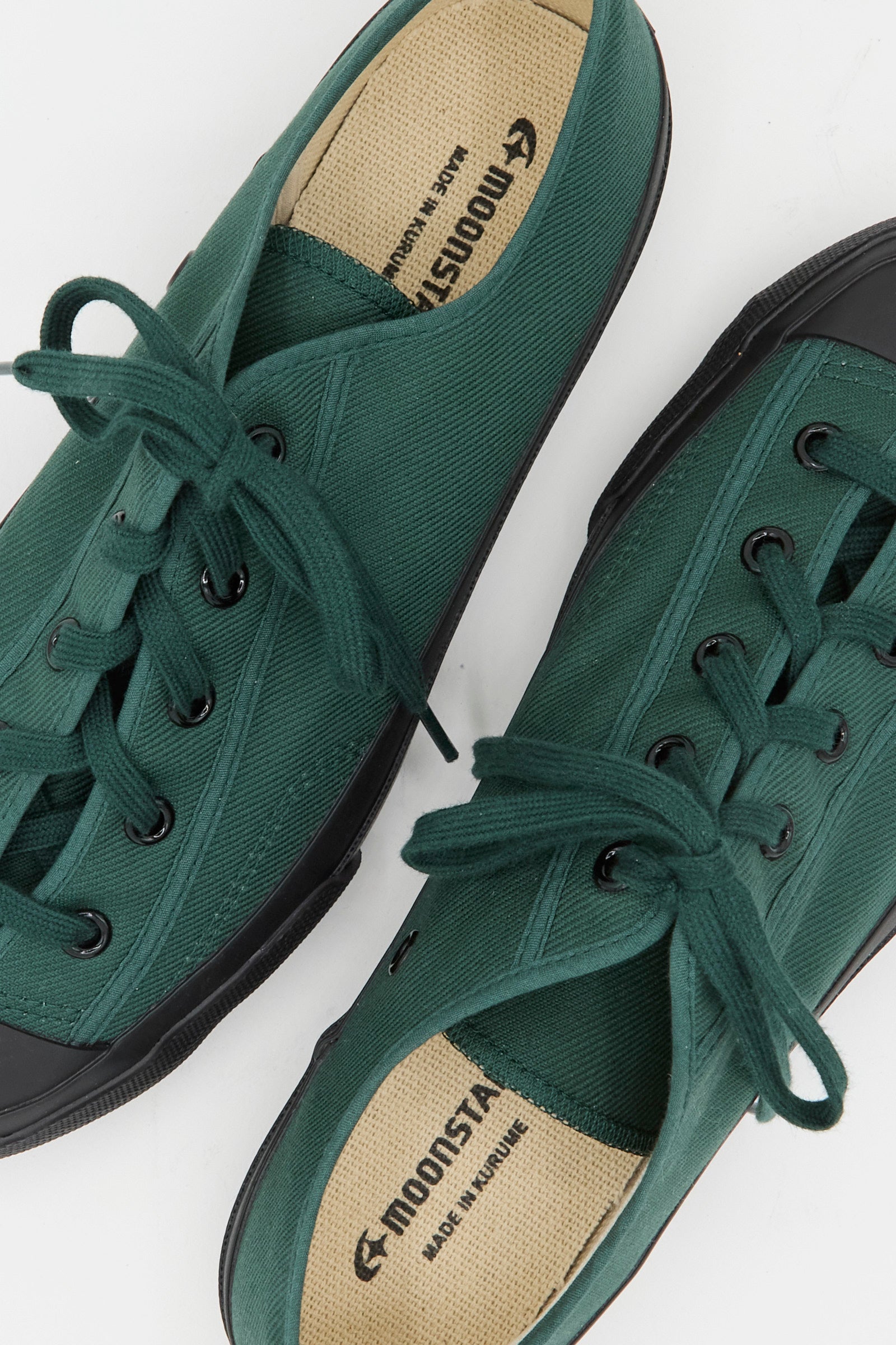 Moonstar Gym Classic Sneaker in Dark Green—crafted in Japan, features green canvas, black rubber toes and soles, laces, and "Moonstar Made in Kurume" branding on the insoles.