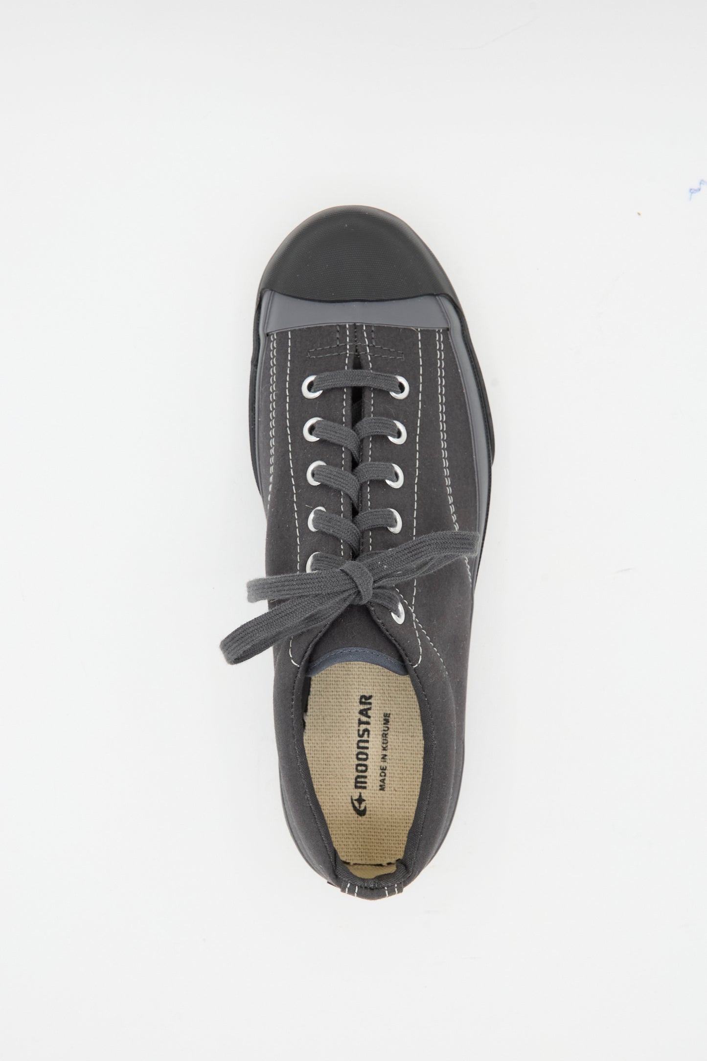 The Moonstar Gym Court Sneaker in Charcoal is a low top, black sneaker with white stitching and laces, made from cotton nylon canvas and branded on the insole. Made in Japan.