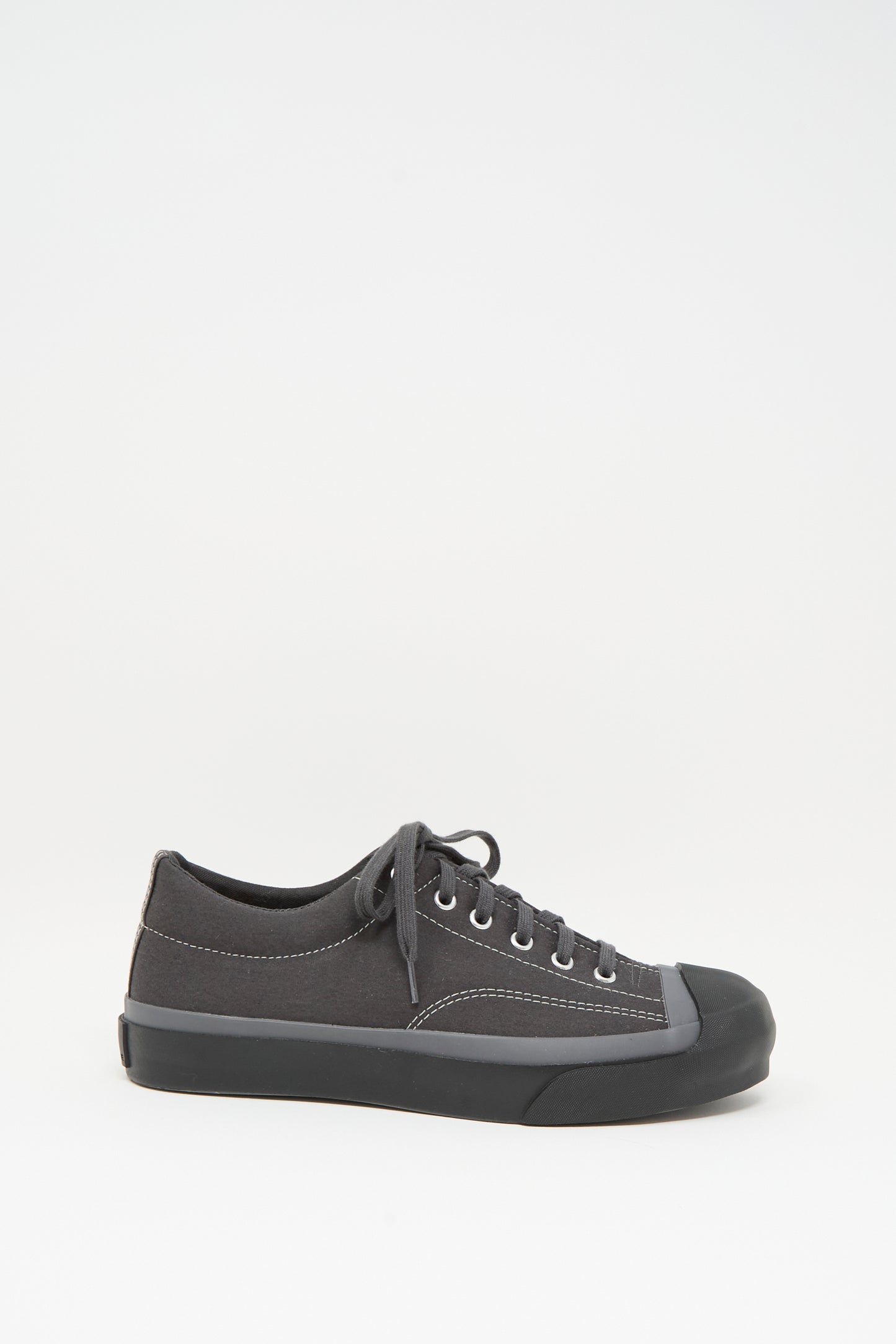 The Moonstar Gym Court Sneaker in Charcoal is a black low-top crafted from cotton nylon canvas with matching laces and a rubber toe cap, shown in side view against a plain white background.