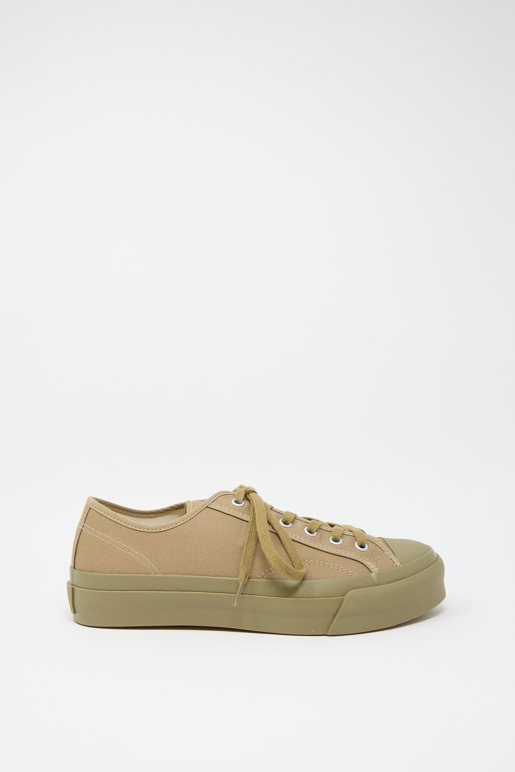 A side view of the Moonstar Low Trainer Sneaker in Khaki, a unisex low trainer in beige and olive green with laces, featuring a canvas rubber sole, set against a plain white background.