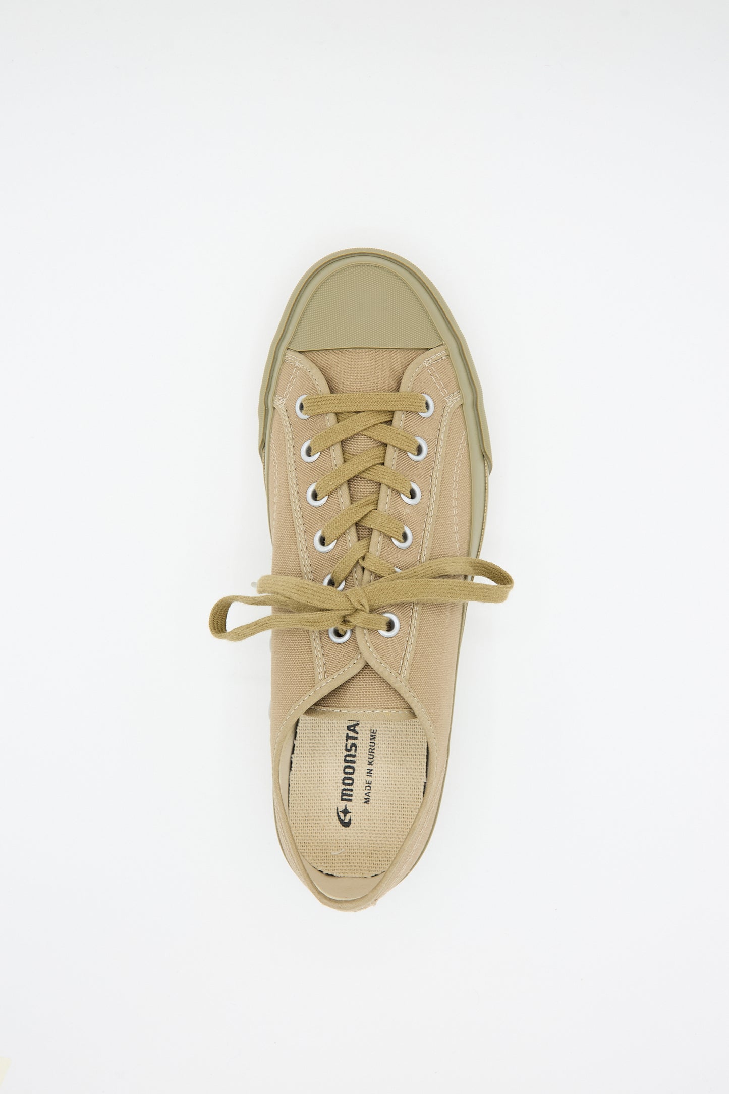 A top-down view of a single Low Trainer Sneaker in Khaki with laces tied in a bow. The shoe features a canvas rubber sole, a rubber toe cap, and the Moonstar name visible on the insole. Handmade in Japan, this sneaker showcases impeccable craftsmanship.