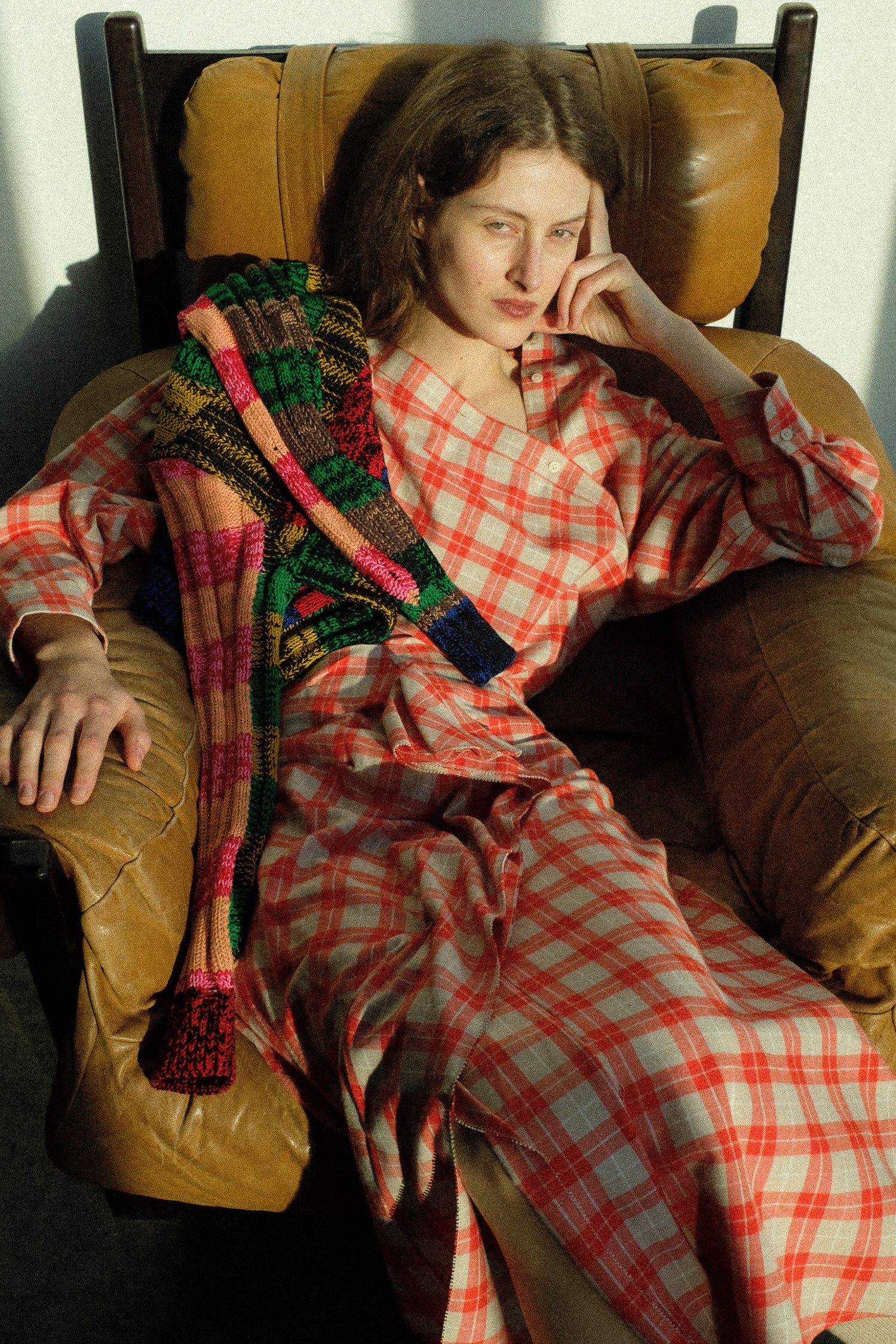 A woman sitting on a chair wearing Rachel Comey's Hollow Top in Red, and Nesom Skirt in Red with her hand on her head.