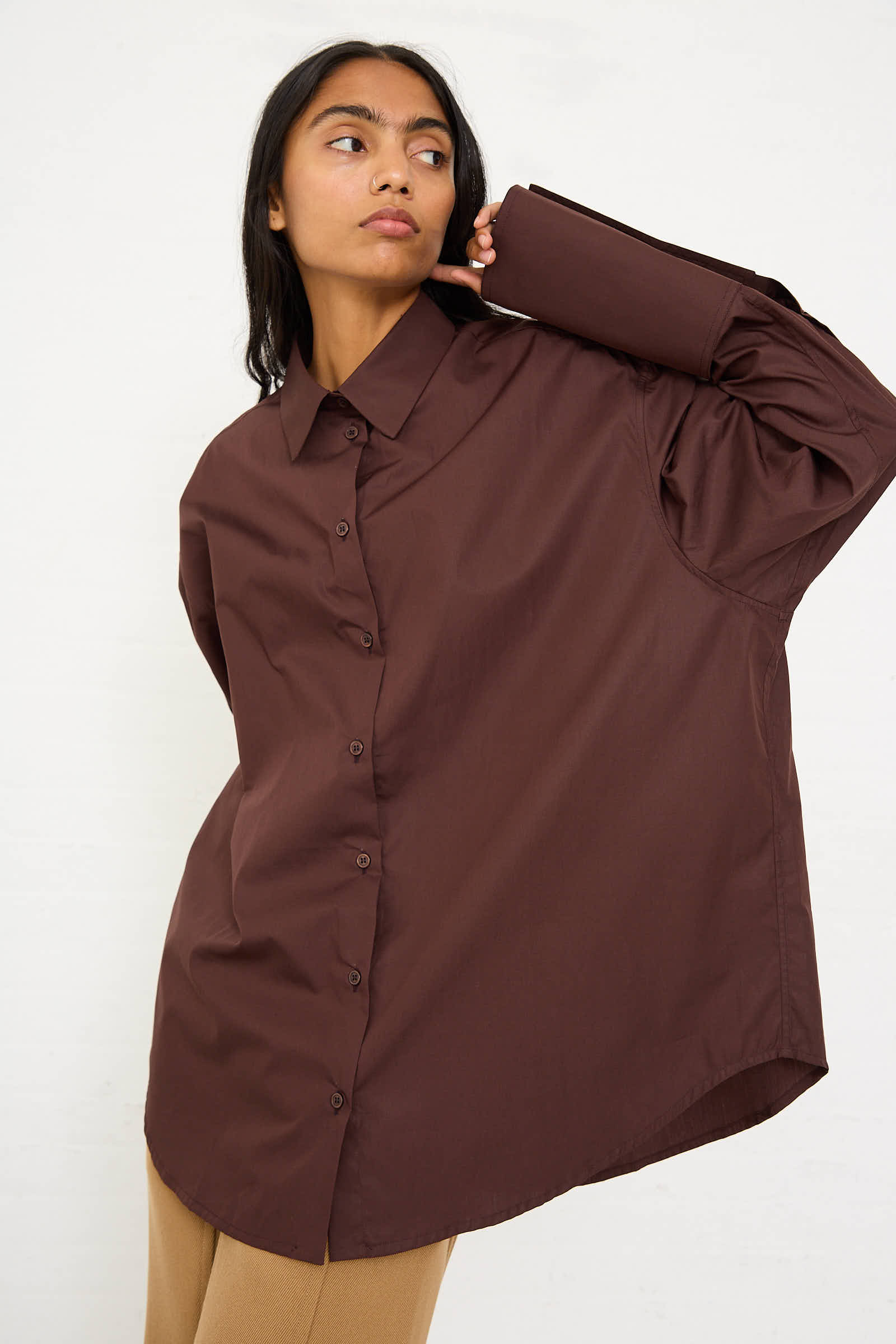 A person wearing a Niccolò Pasqualetti Cotton Poplin Classico Shirt in Brown and tan pants looks slightly to the side against a plain background.