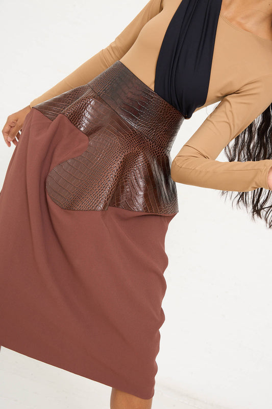 A person is wearing a tan and black top paired with a brown leather peplum belt and the Niccolò Pasqualetti Croc Embossed Leather and Viscose Crepe Onda Skirt in Brown and Burnt Brown.