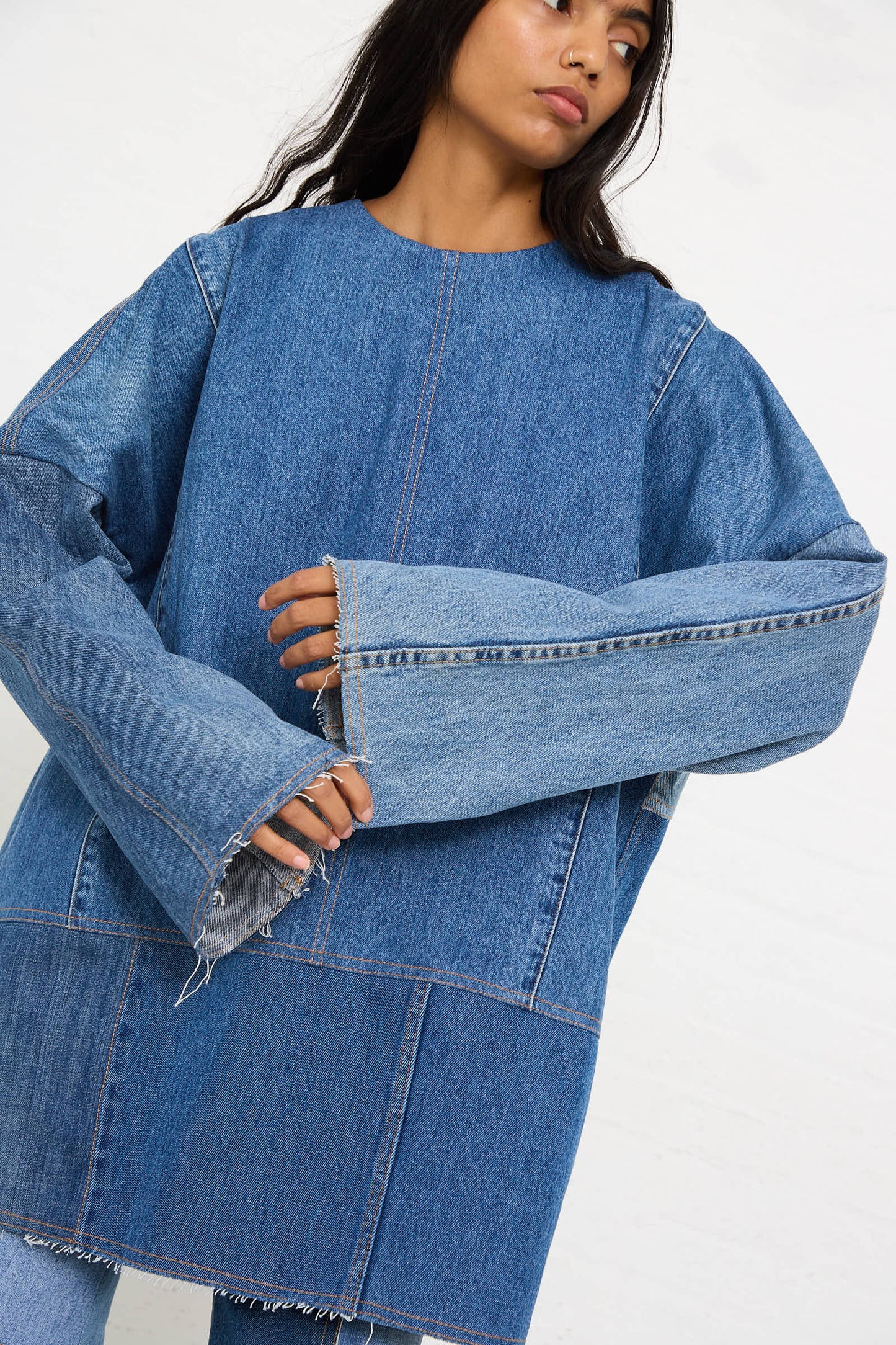 A person wearing the Salvaged Jean Patchwork Raglan Shirt in Blue by Niccolò Pasqualetti.