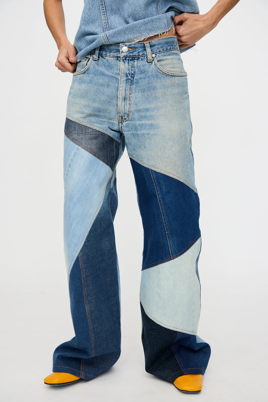 A person wears Niccolò Pasqualetti Salvaged Jean Patchwork Ritaglio Trousers in blue denim (100% cotton), paired with yellow pointed-toe shoes. Only the lower half and part of the upper body are visible.