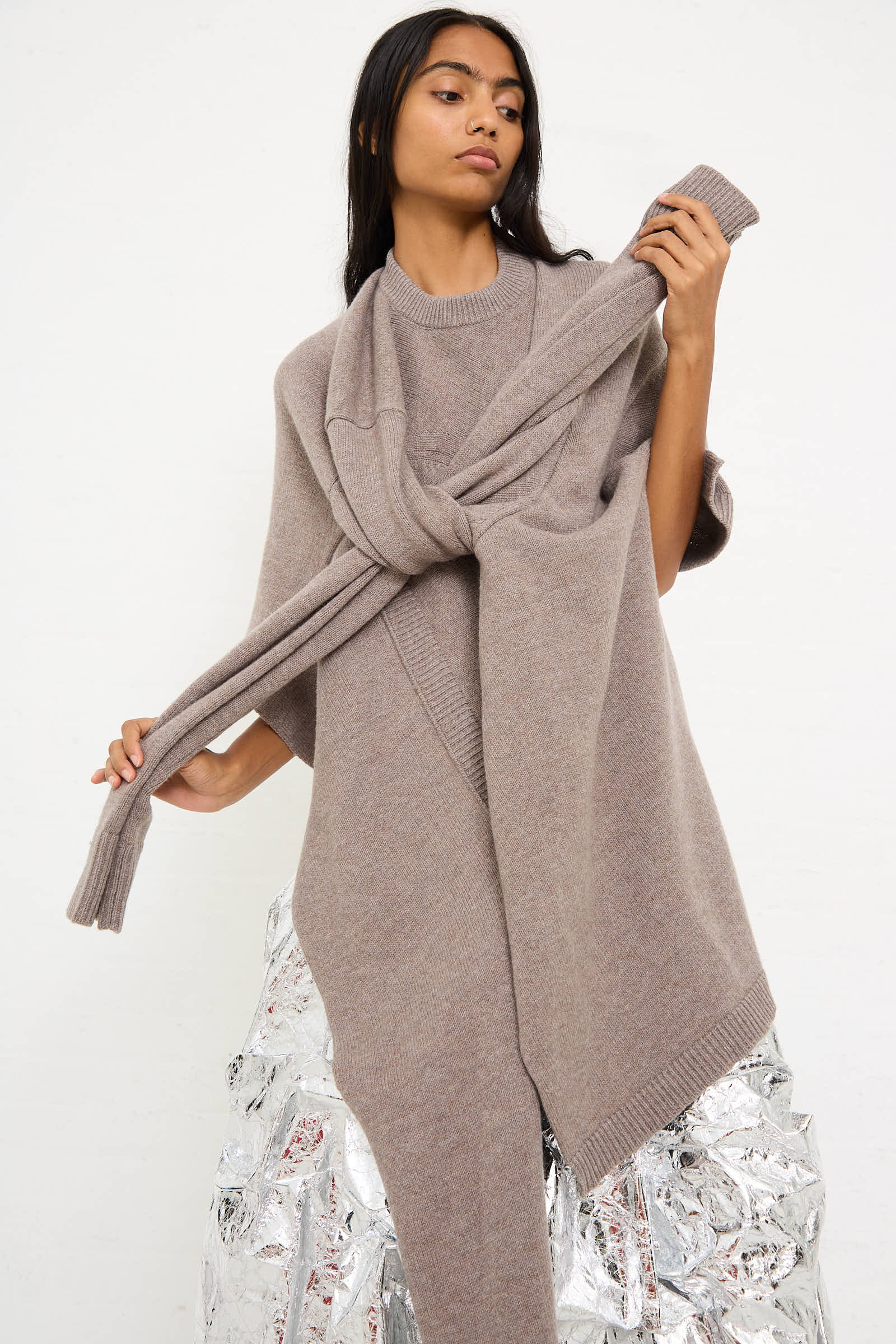 A person wearing a cozy, Niccolò Pasqualetti Wool Cashmere Blend Massa Knit Sweater in Light Brown with an oversized fit and a similarly colored scarf stands against a plain white background.