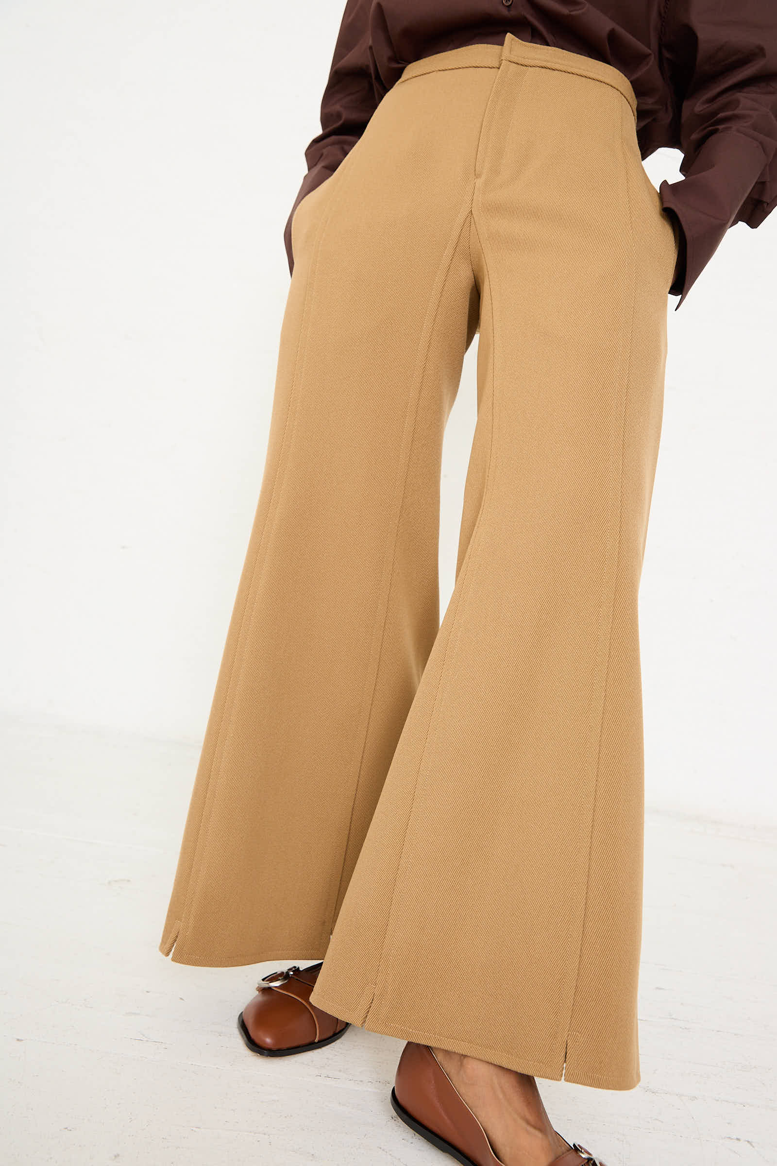 A person wearing Niccolò Pasqualetti's Wool Drill Tegola Trouser in Antique Bronze with hands in pockets, paired with brown leather shoes, photographed from the waist down.