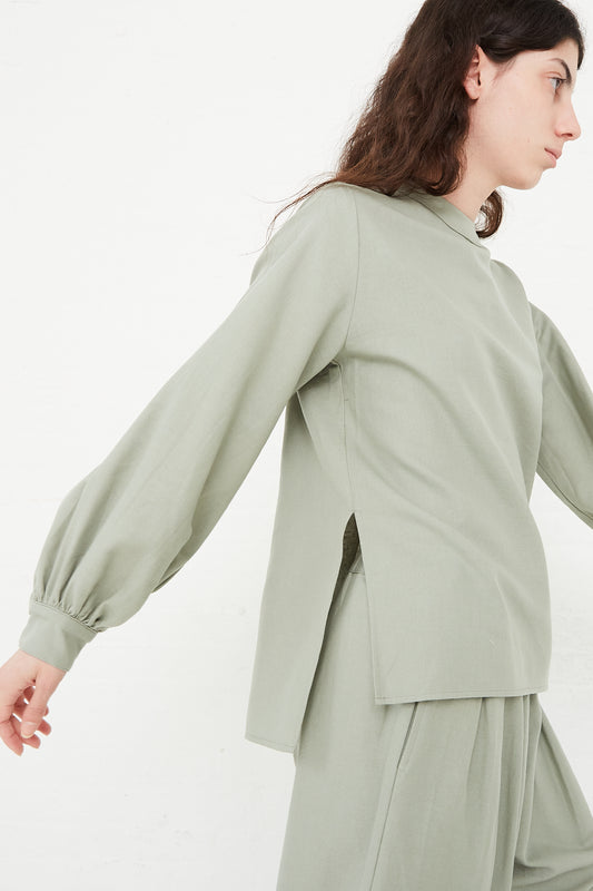 The model is wearing a Cotton Twill Puff Sleeve Blouse in Agave by Black Crane. Side view.