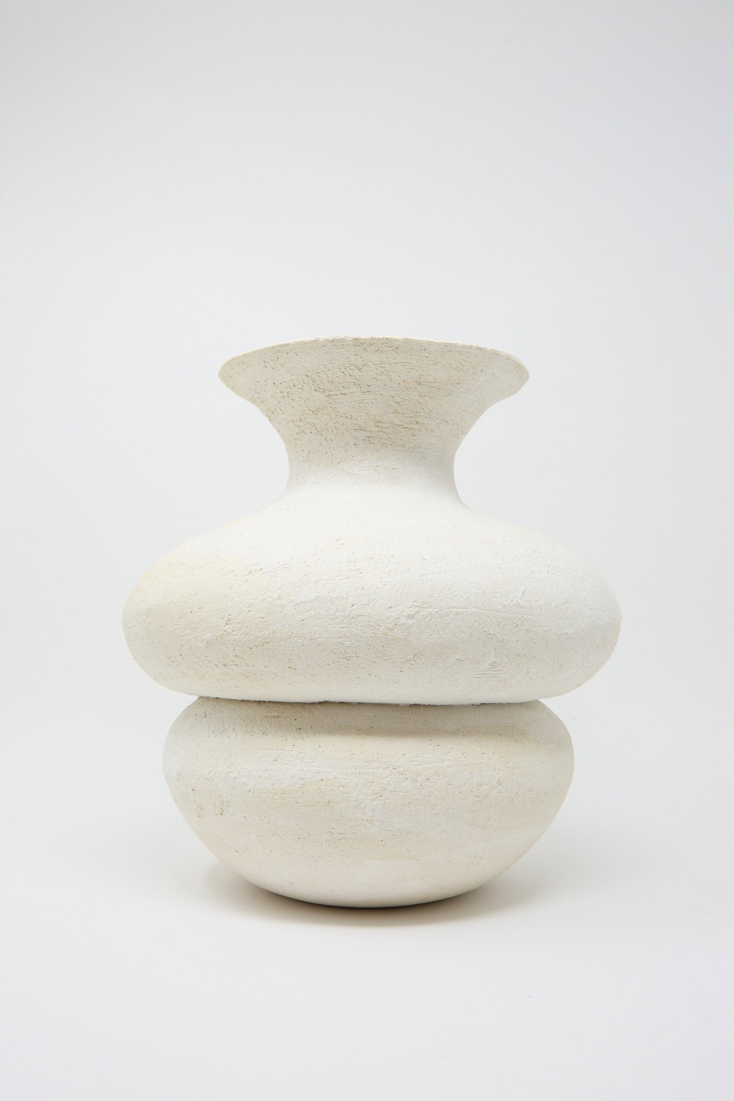 Crafted by Oatmeal in Pennsylvania, the Double Bottom Vessel is a white, textured ceramic piece with a wide, round base and narrow neck, presented against a plain background.