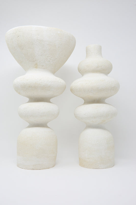 Two Monolith Vessels by Oatmeal, featuring stacked, rounded shapes in a handmade white stone design, stand side by side against a plain background.