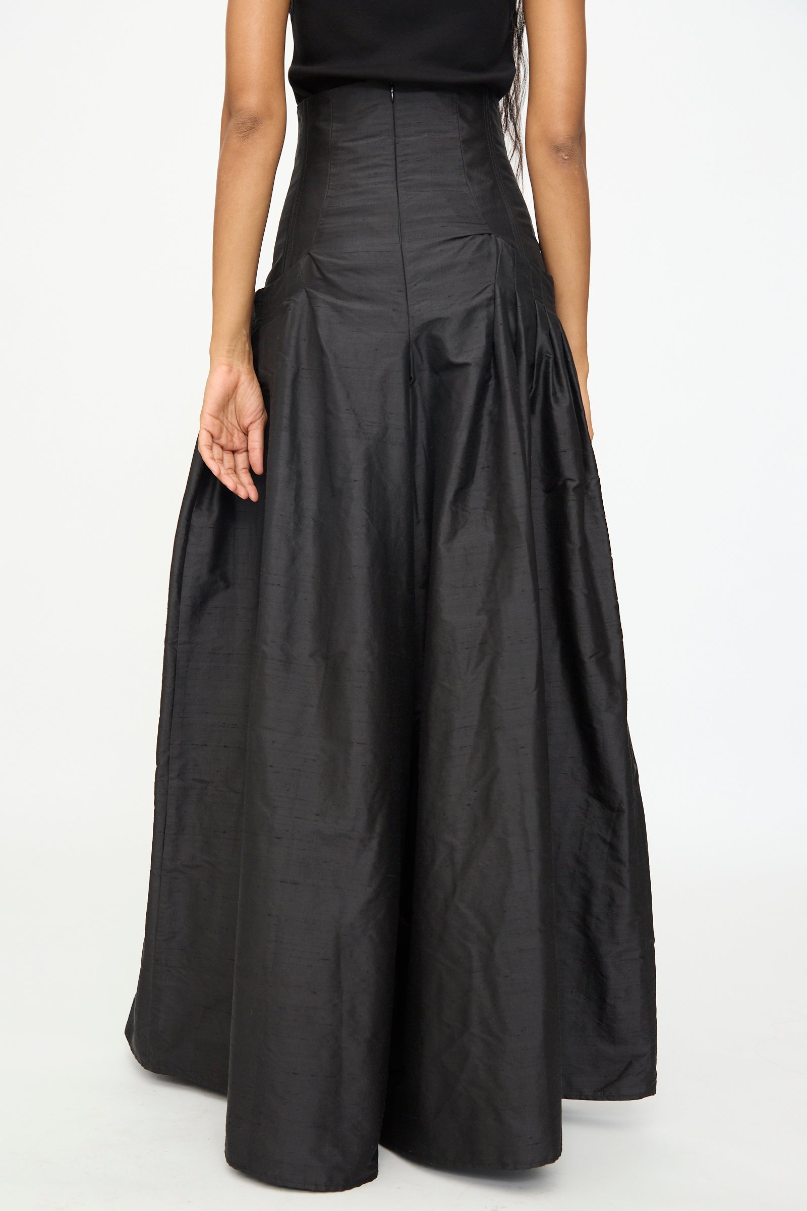 A person wearing the Robbie Pant in Black by Olivia Cashmore, featuring a high-waisted silhouette and luxurious silk-blend fabric, viewed from the back against a plain background.