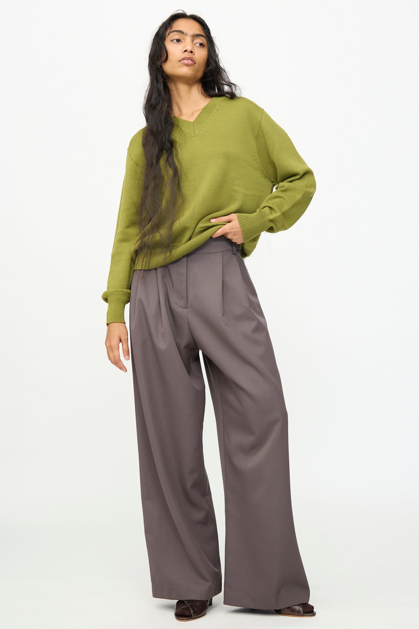 A person stands against a plain white background wearing an olive green sweater and the Wool Marco Pant in Mud by Olivia Cashmore.