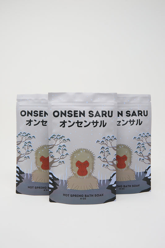 Two packages of Onsen Saru hot spring bath soak featuring a monkey graphic and infused with essential oils, displayed against a white background.