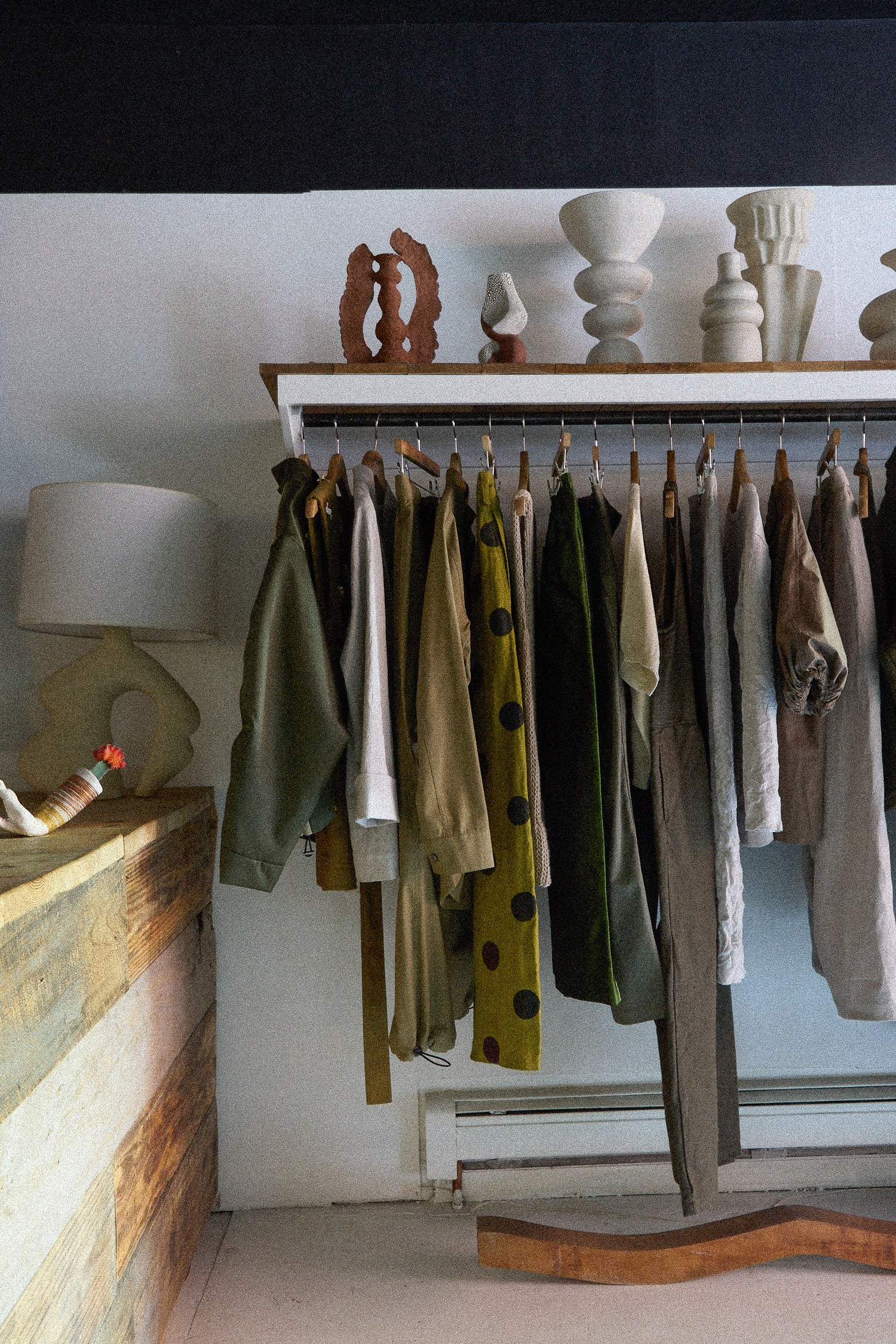 Clothing rack with various garments against a white wall.