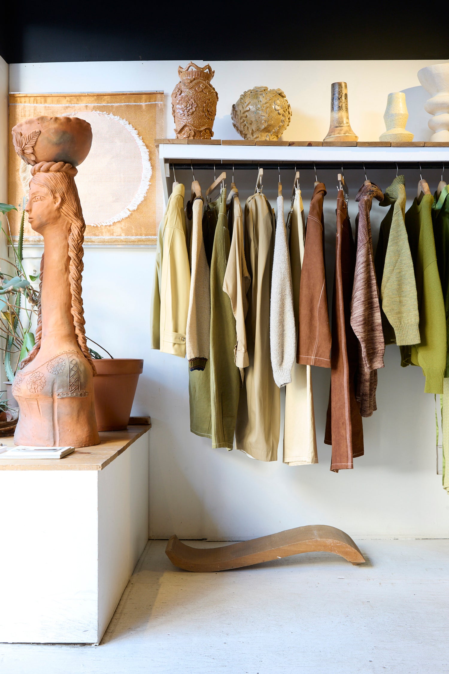An image of the inside of Oroboro Store, featuring a clothing rack, ceramics and terracotta bust.