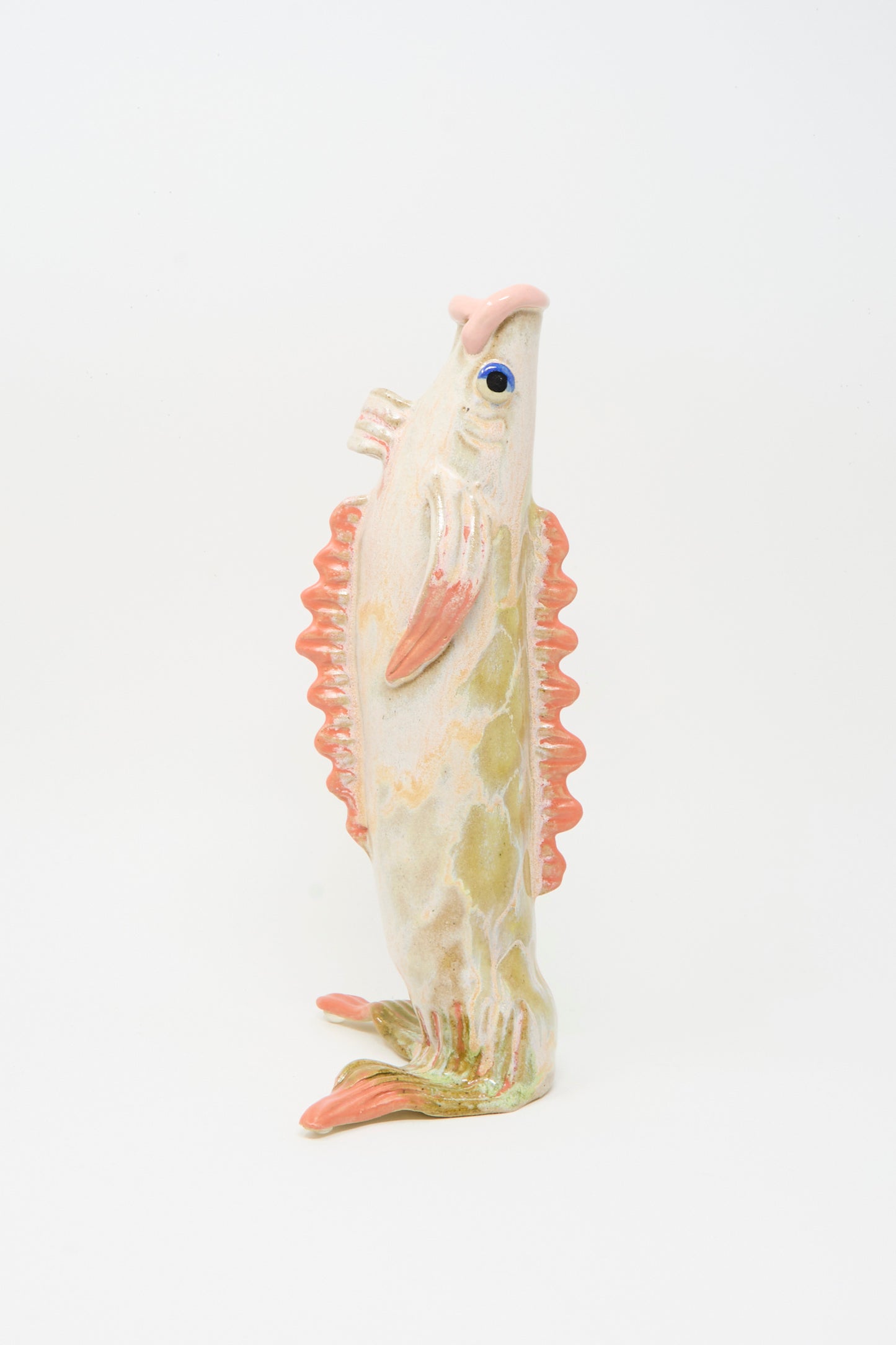 The Fish Vase in Coral III by Pearce Williams is a ceramic vase with orange fins and a textured off-white body, shaped like a fish and standing upright against a plain white background.