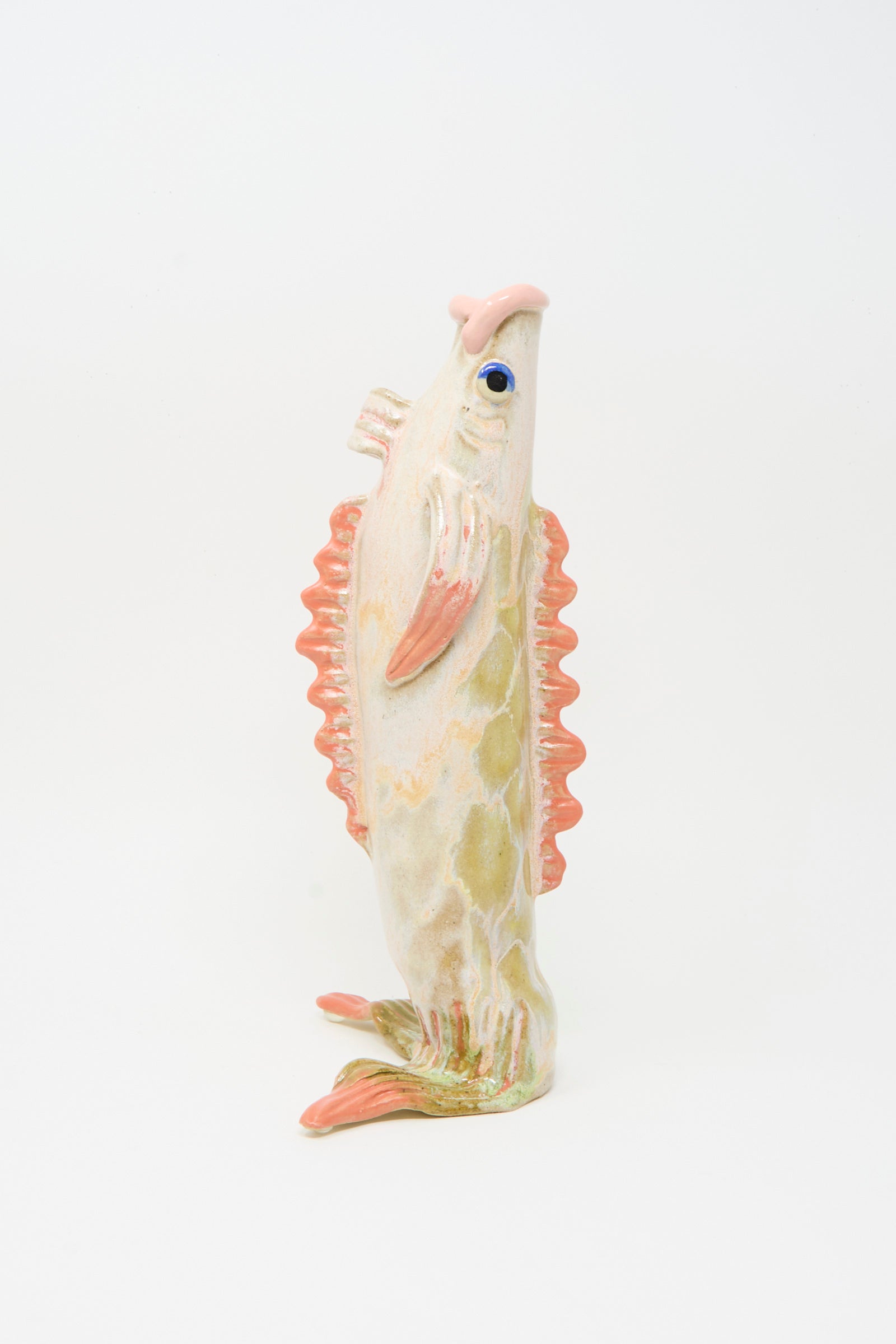 The Fish Vase in Coral III by Pearce Williams is a ceramic vase with orange fins and a textured off-white body, shaped like a fish and standing upright against a plain white background.