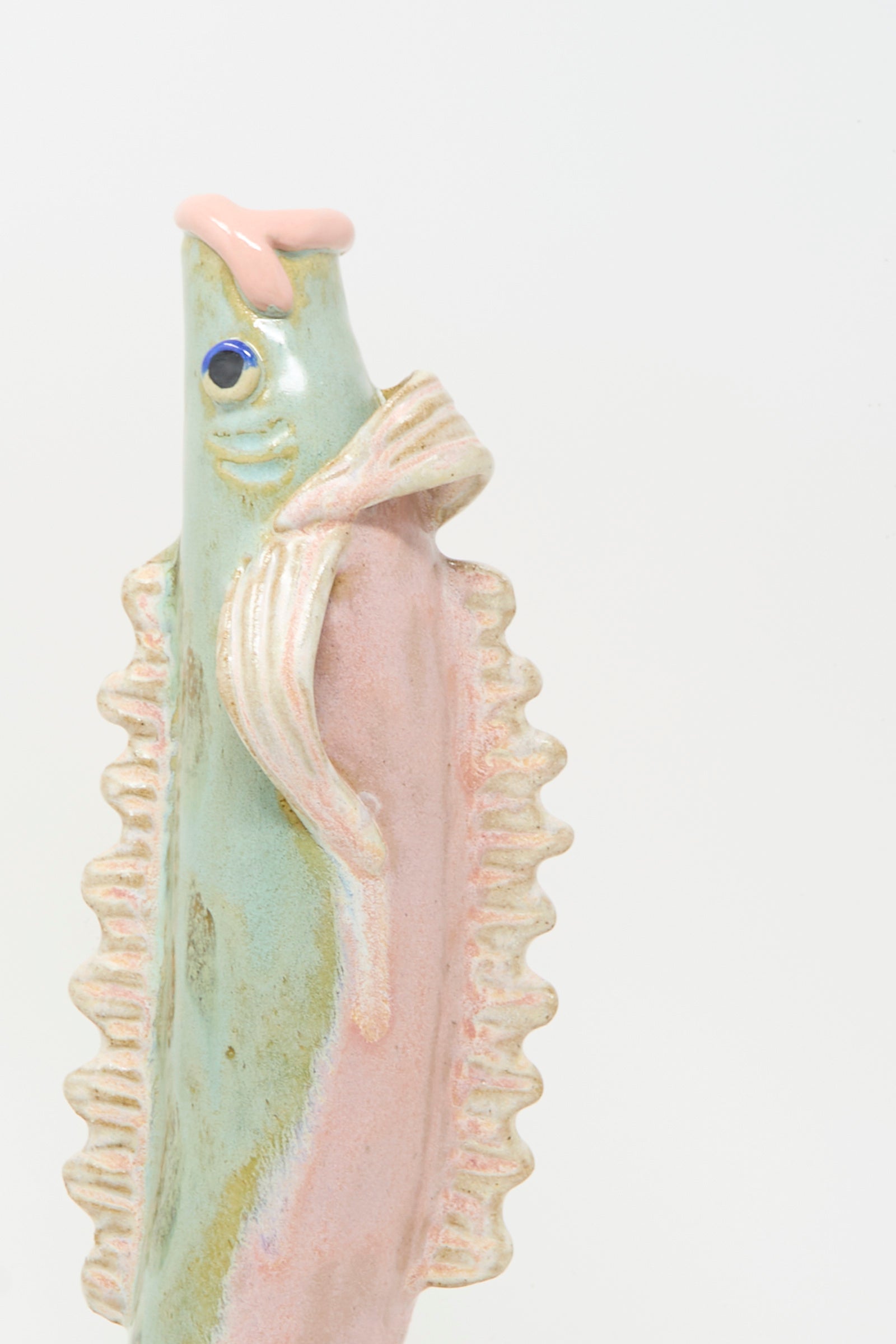 The Pearce Williams Fish Vase in Green is a handmade stoneware piece with textured fins, smooth surface, and pastel green, pink, and cream hues—an eye-catching decor accent shown against a plain white background.