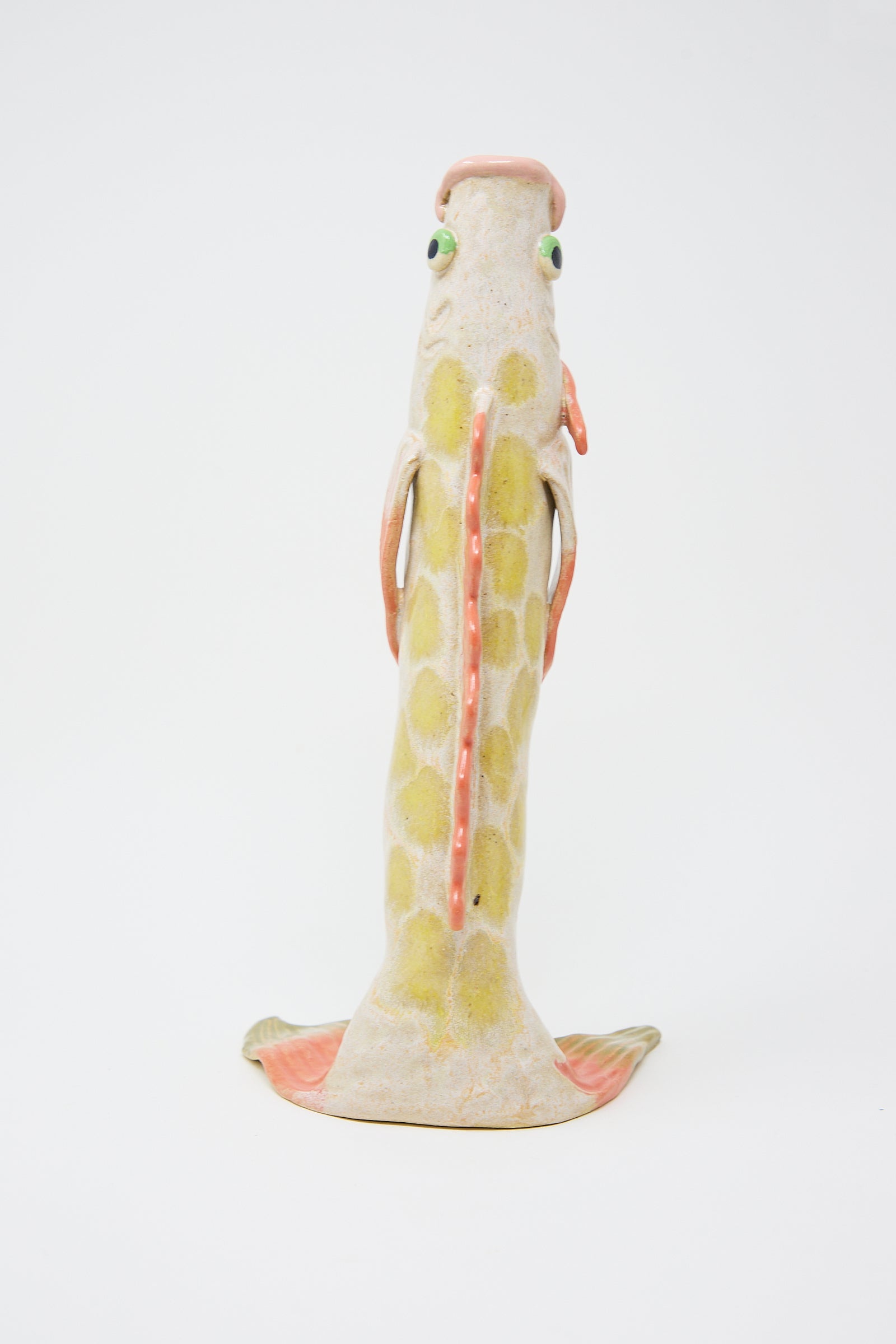 Ceramic figurine of a whimsical, upright koi fish with large eyes, painted in subtle shades of yellow, red, and green, standing on a base that simulates fins – Pearce Williams Fish Vase in Pink.