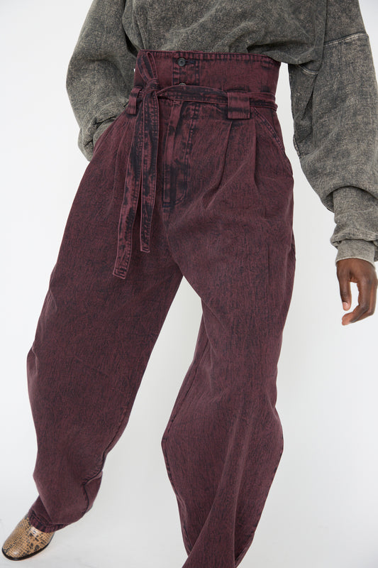 A woman wearing the Acid Madrona Denim Bowman Pant in Boisonberry by Rachel Comey, paired with a gray long-sleeved top, seen from below the torso.