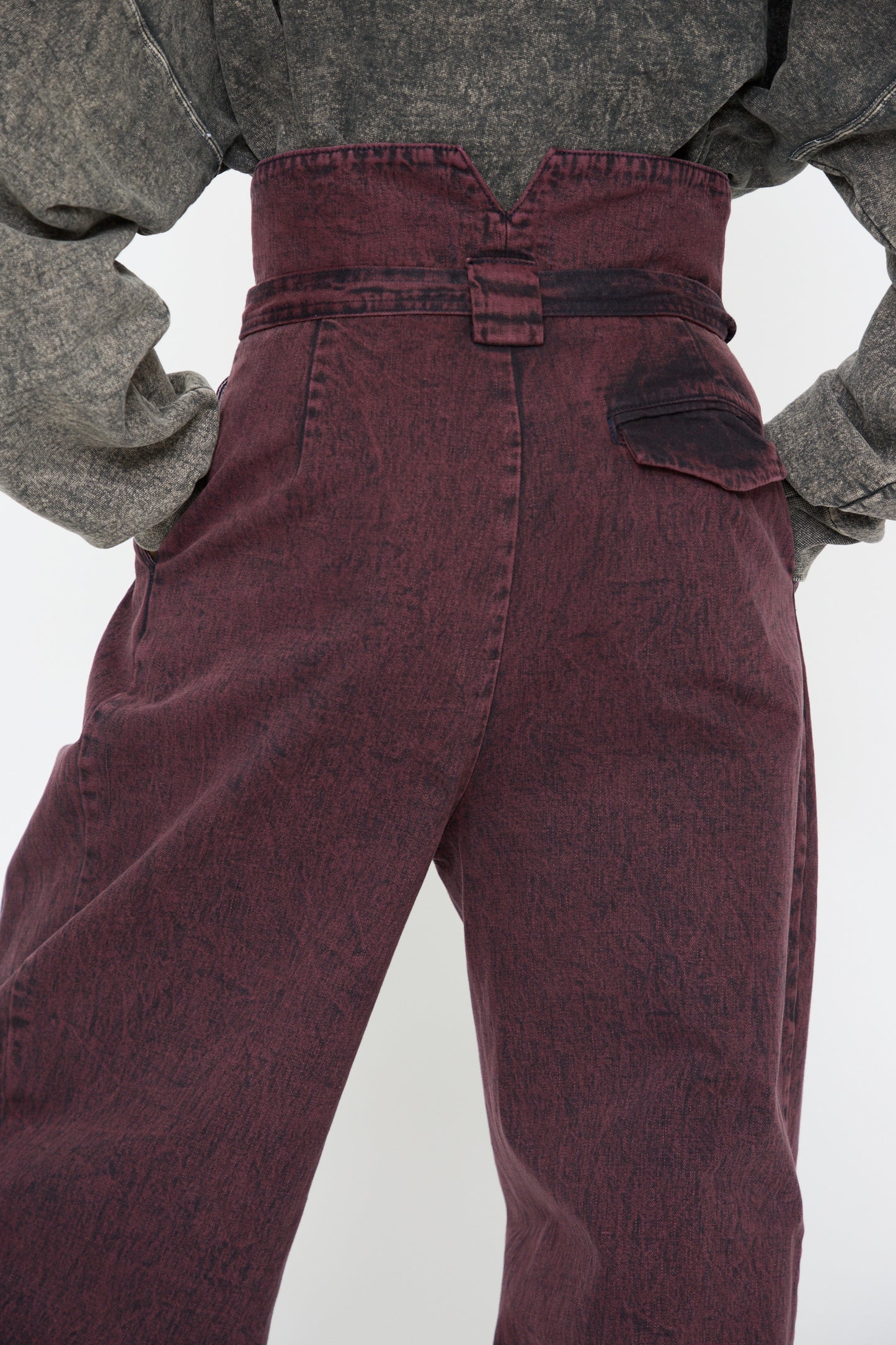 A close up of the back of a woman wearing the Acid Madrona Denim Bowman Pant in Boisonberry by Rachel Comey, featuring high-waisted styling with a self-tie belt.