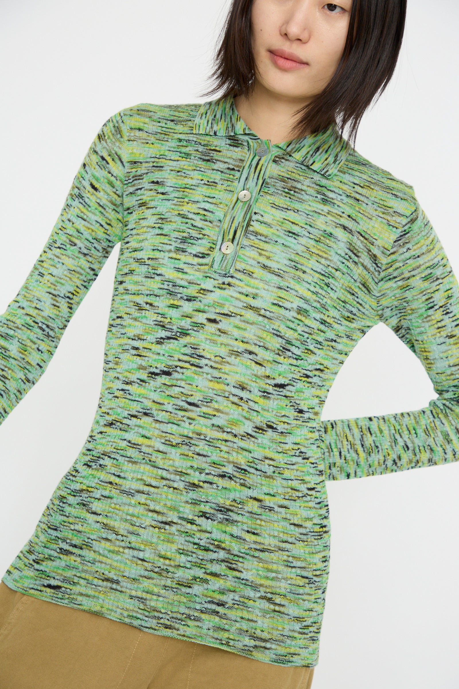 Against a plain white background, a person wears the Rachel Comey Avril Polo in Lime Multi Spacedye, a green and black patterned long-sleeve sweater made from space-dyed yarn for a unique color blend.