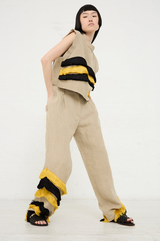 A woman in a Rachel Comey Bacchus Top in Natural with black and yellow fringe details posing against a white background.
