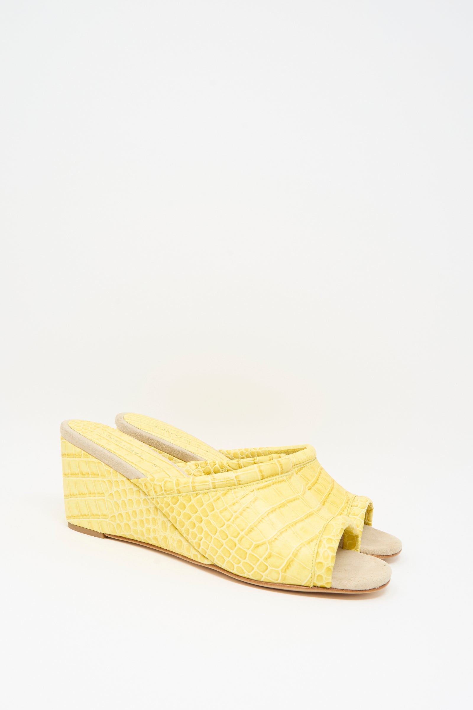 The Rachel Comey Bully Mule in Banana is a pair of yellow wedge sandals with crocodile and subtle snakeskin textures, featuring open toes and slingback straps, displayed on a plain white background.