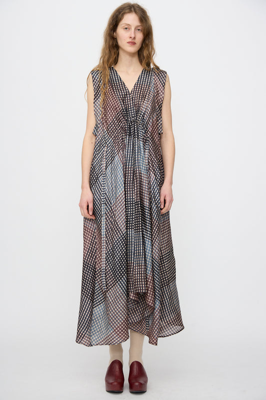 A woman faces forward wearing the Rachel Comey Clement Dress in Juniper, a sleeveless, loose-fitting, block printed maxi handmade in India, with red closed-toe shoes against a plain white background.