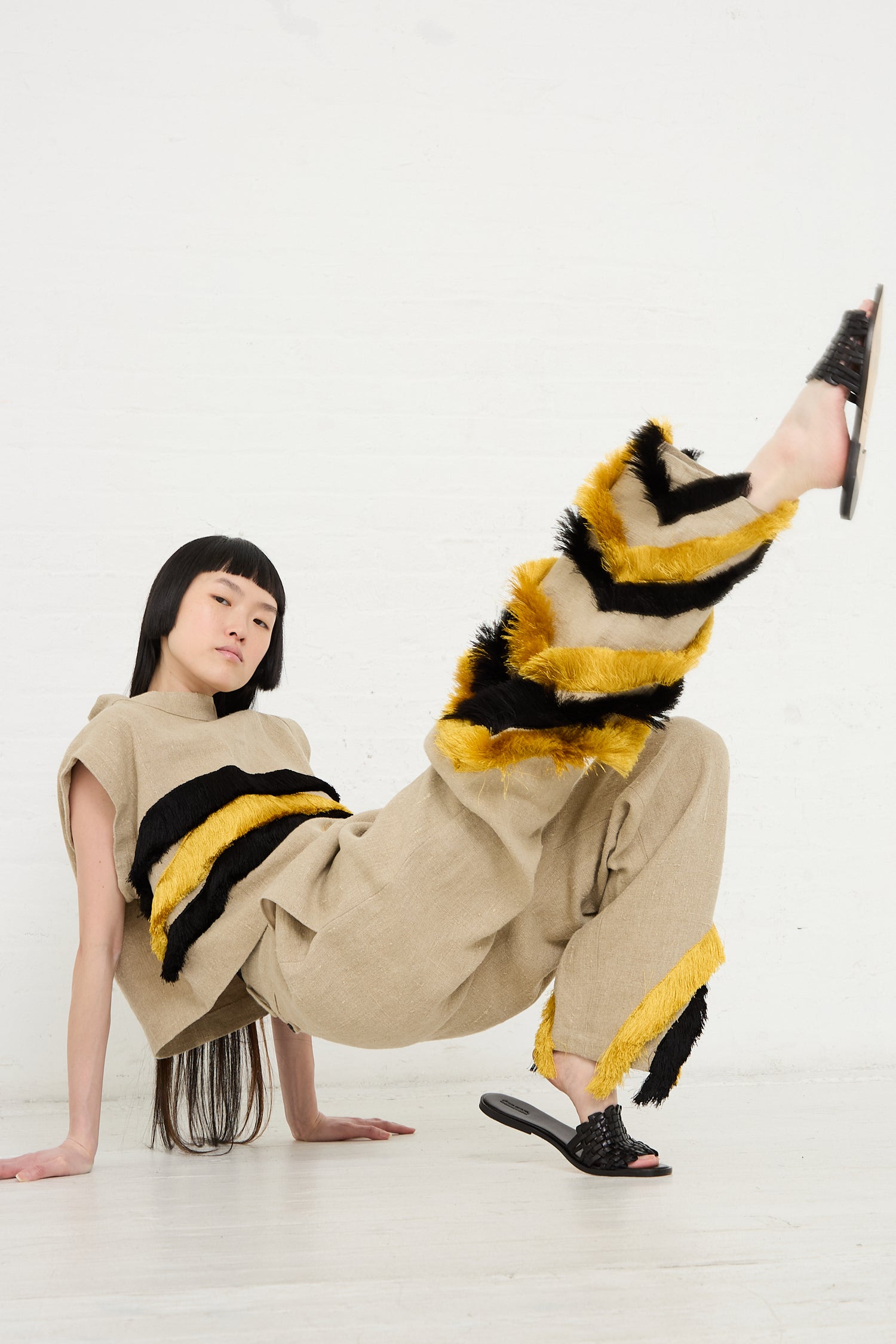 Woman performing a dance move in Rachel Comey's Ditto Pant in Natural with yellow and black stripes.