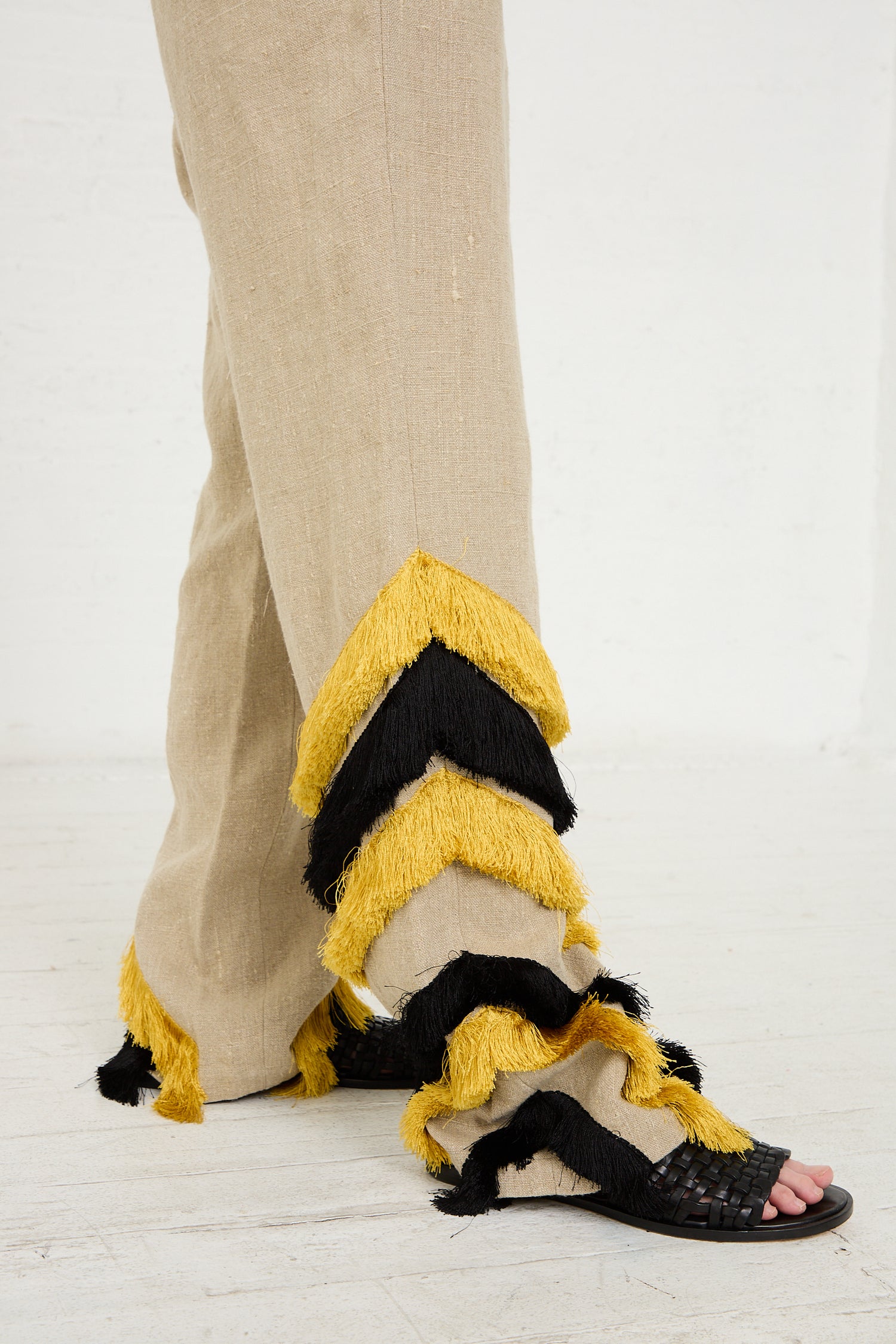 A person wearing the Rachel Comey Ditto Pant in Natural and a distinctive black and yellow fringed shoe from the Rachel Comey design.