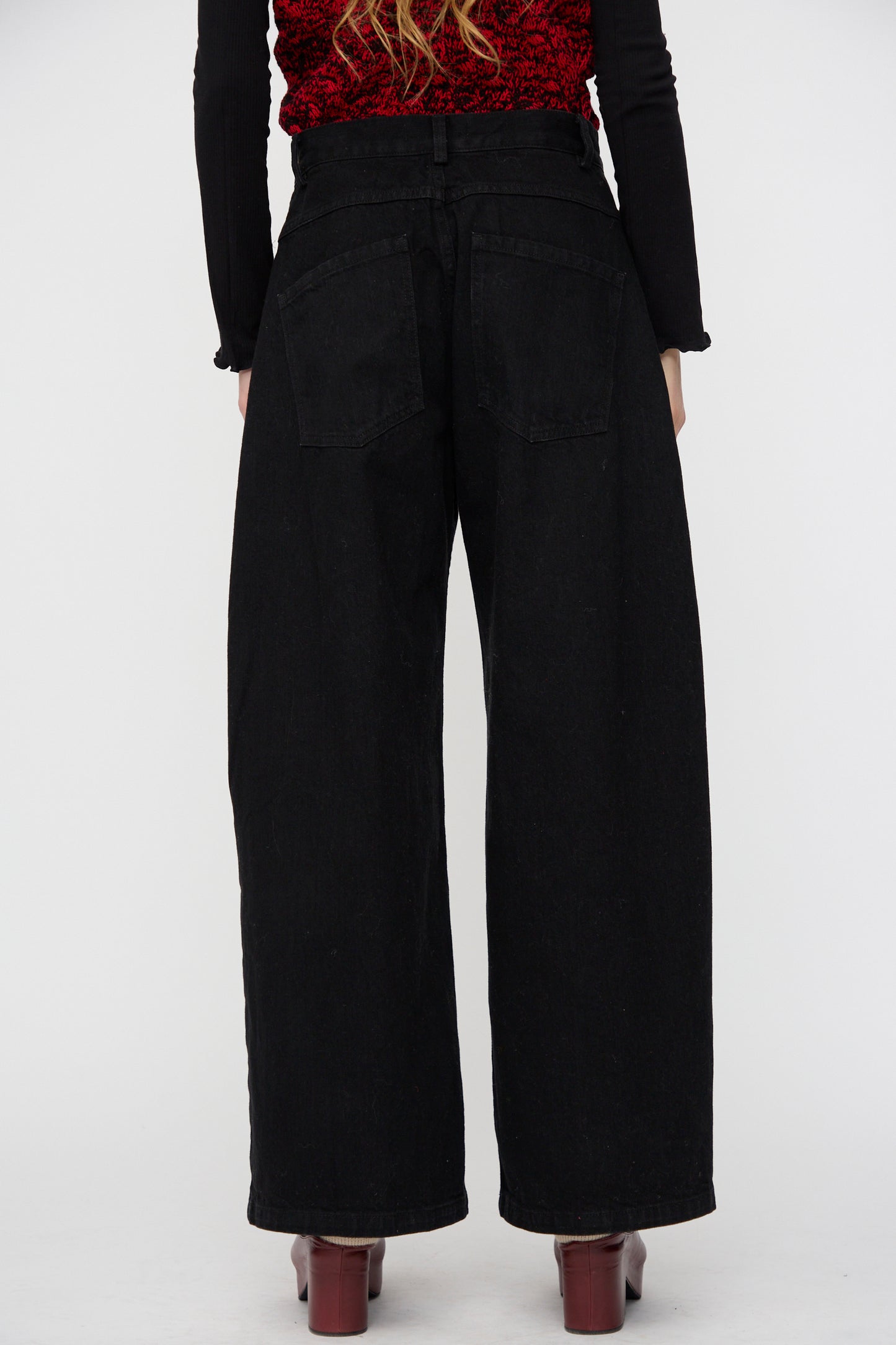 Model wearing the Rachel Comey Dottir Pant in Black, styled with a red textured top and photographed from the back against a plain white background.