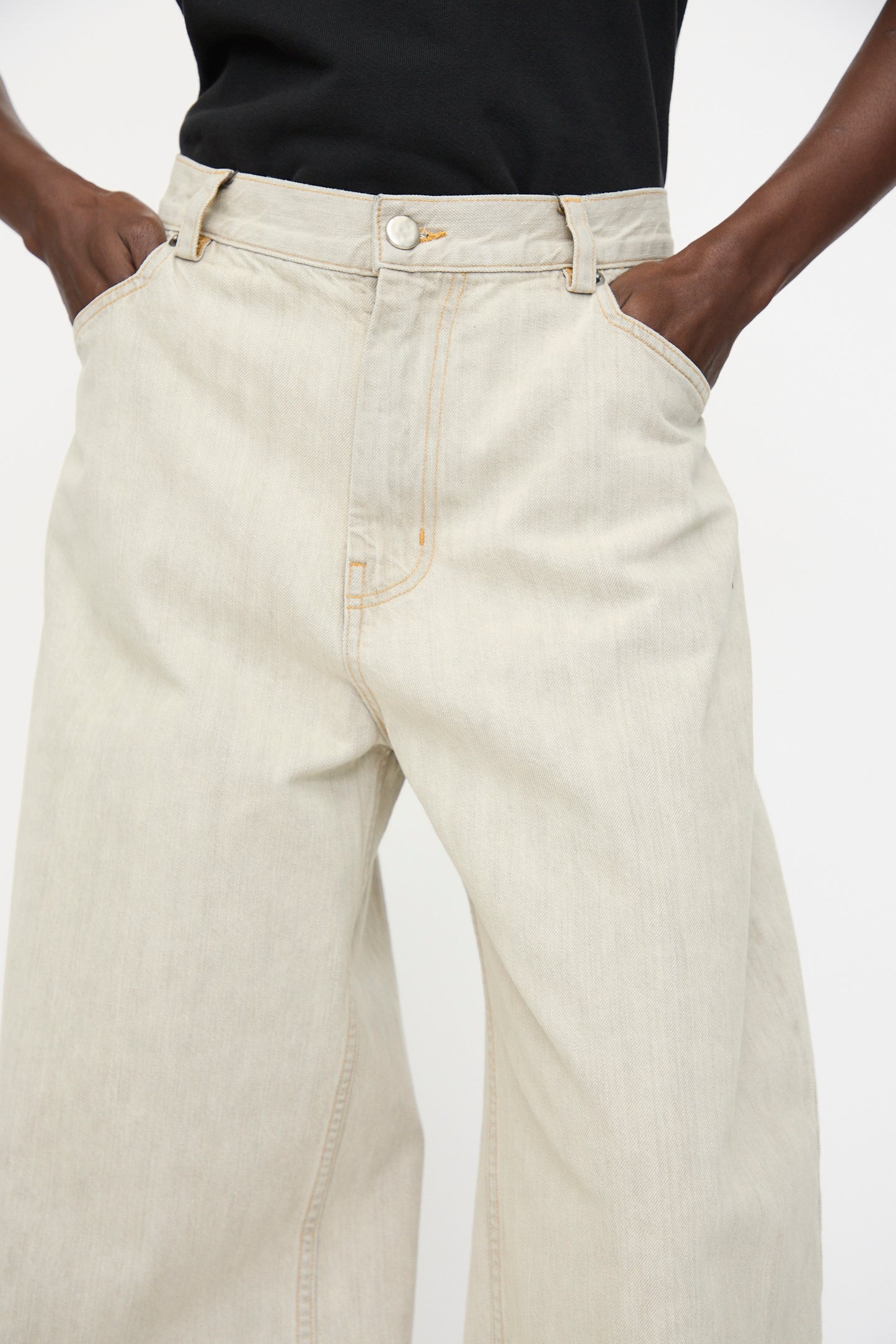 A person wearing the Rachel Comey Dottir Pant in Khaki Wash and a black shirt, hands in their pockets, shown from waist to mid-thigh.