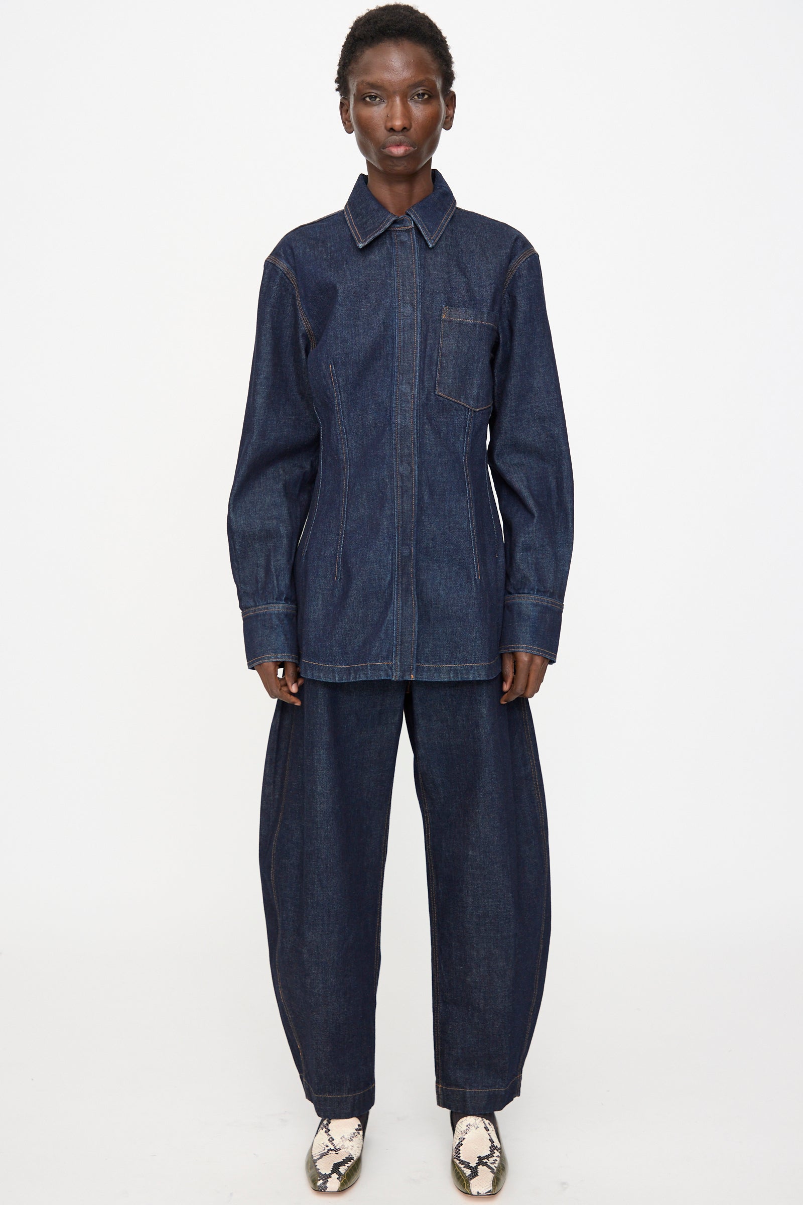 A person faces forward wearing the Rachel Comey Filt Top in Raw Wash, paired with matching wide-leg denim pants and light-colored snakeskin shoes, set against a plain white background.