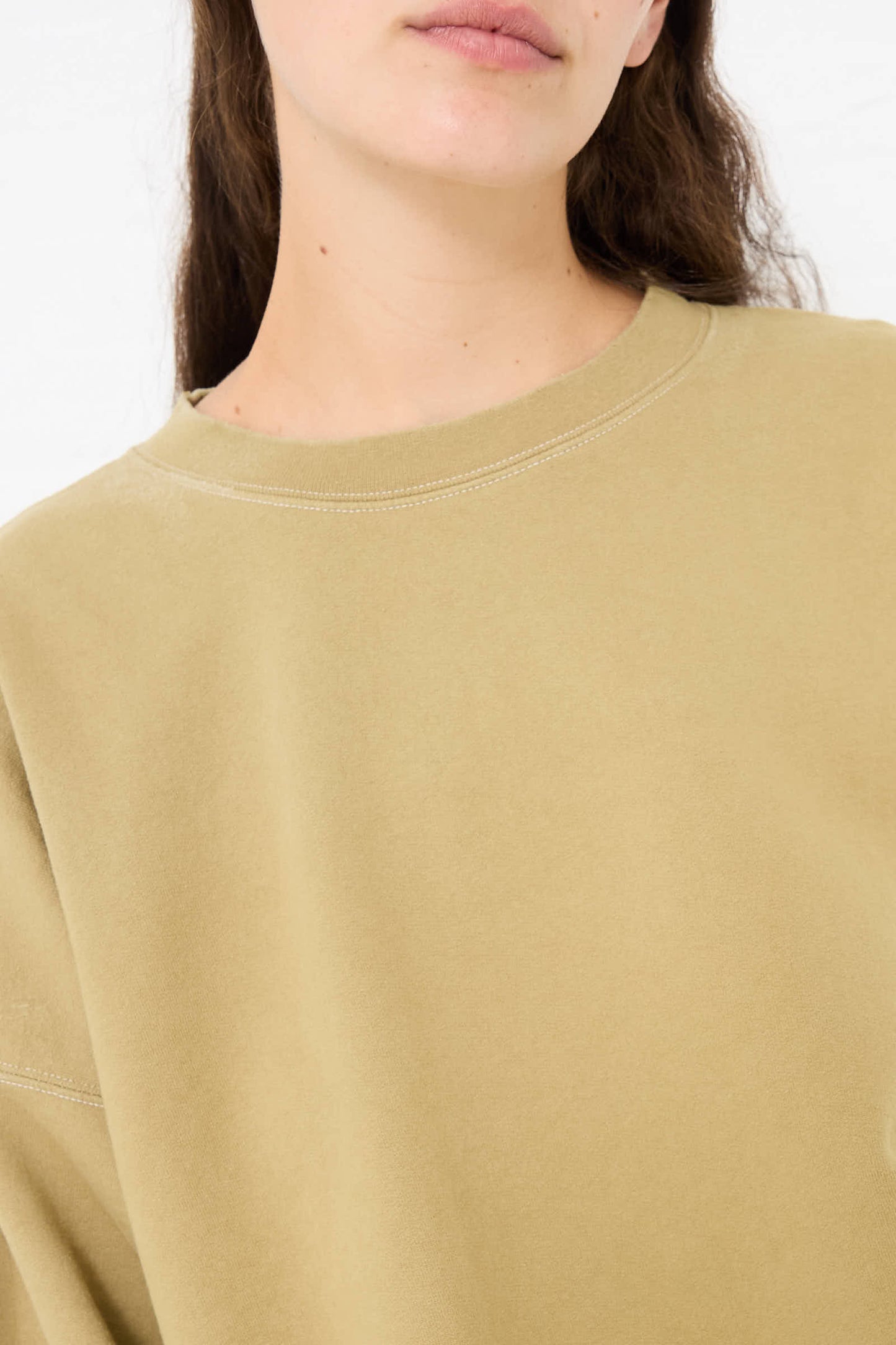 Close-up of a person wearing the Rachel Comey Fond Sweatshirt in Dusty Sage with voluminous cropped sleeves. The background is plain white.