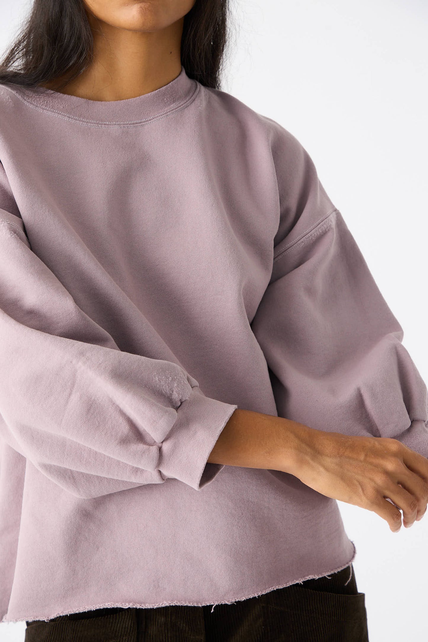 Person wearing the Rachel Comey Fond Sweatshirt in Mauve, a genderless oversized top featuring balloon sleeves and a raw edge hemline, against a plain white background.