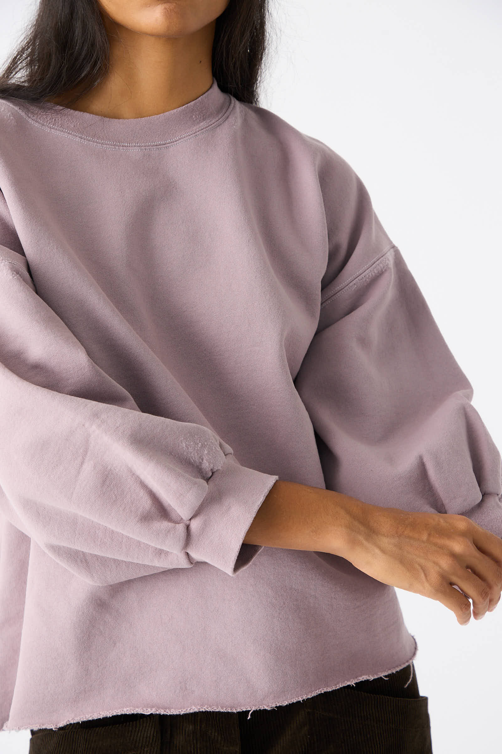 Person wearing the Rachel Comey Fond Sweatshirt in Mauve, a genderless oversized top featuring balloon sleeves and a raw edge hemline, against a plain white background.