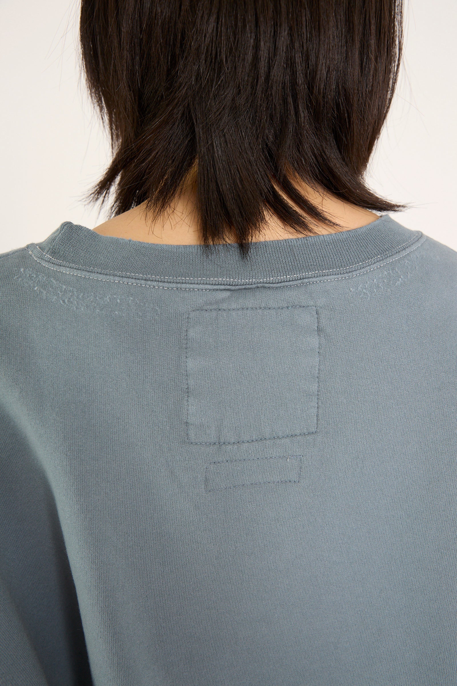 Back view close-up of a person with short dark hair wearing the Fonder Sweatshirt in Petrol by Rachel Comey, designed for an oversized fit.